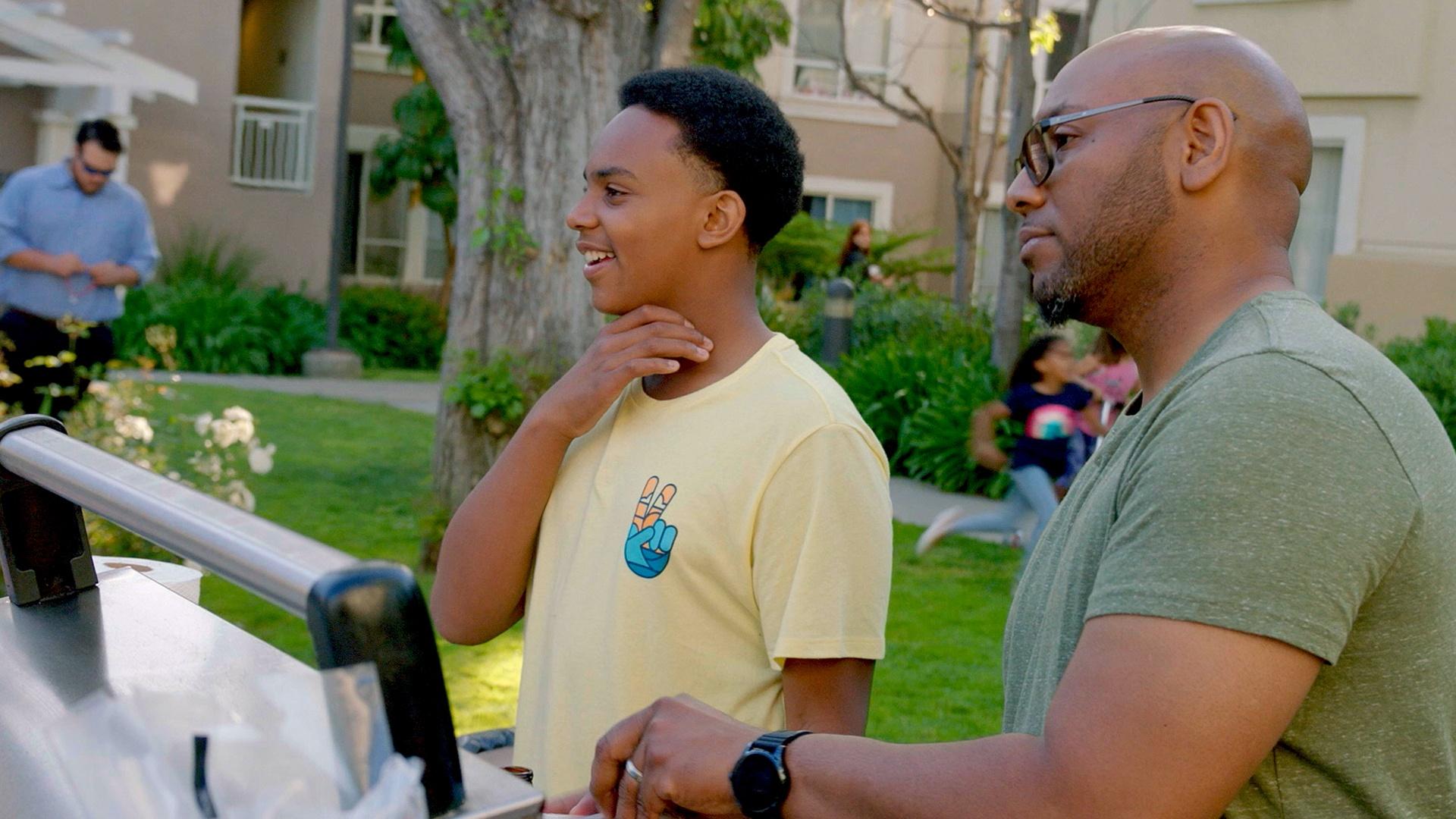 Dell Parks, a young autistic man, assisting his dad Wendell at a neighborhood cookout.