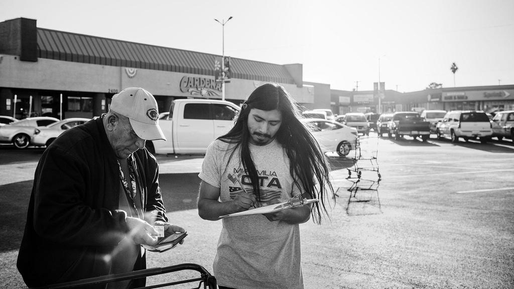 Mi Familia Vota canvasser registers voters outside of Latino grocery store Cardenas.
