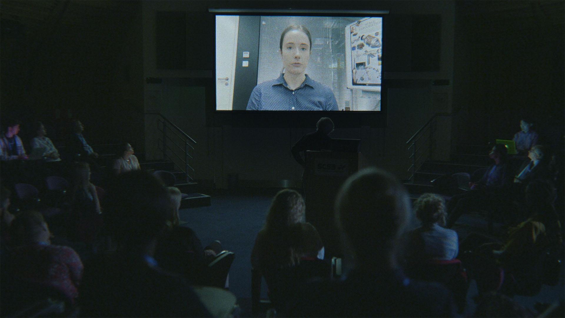 A scientist gives a presentation via video call to a conference audience.