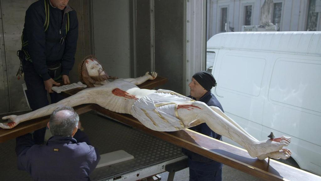 Workers moving a crucifix within the Vatican.