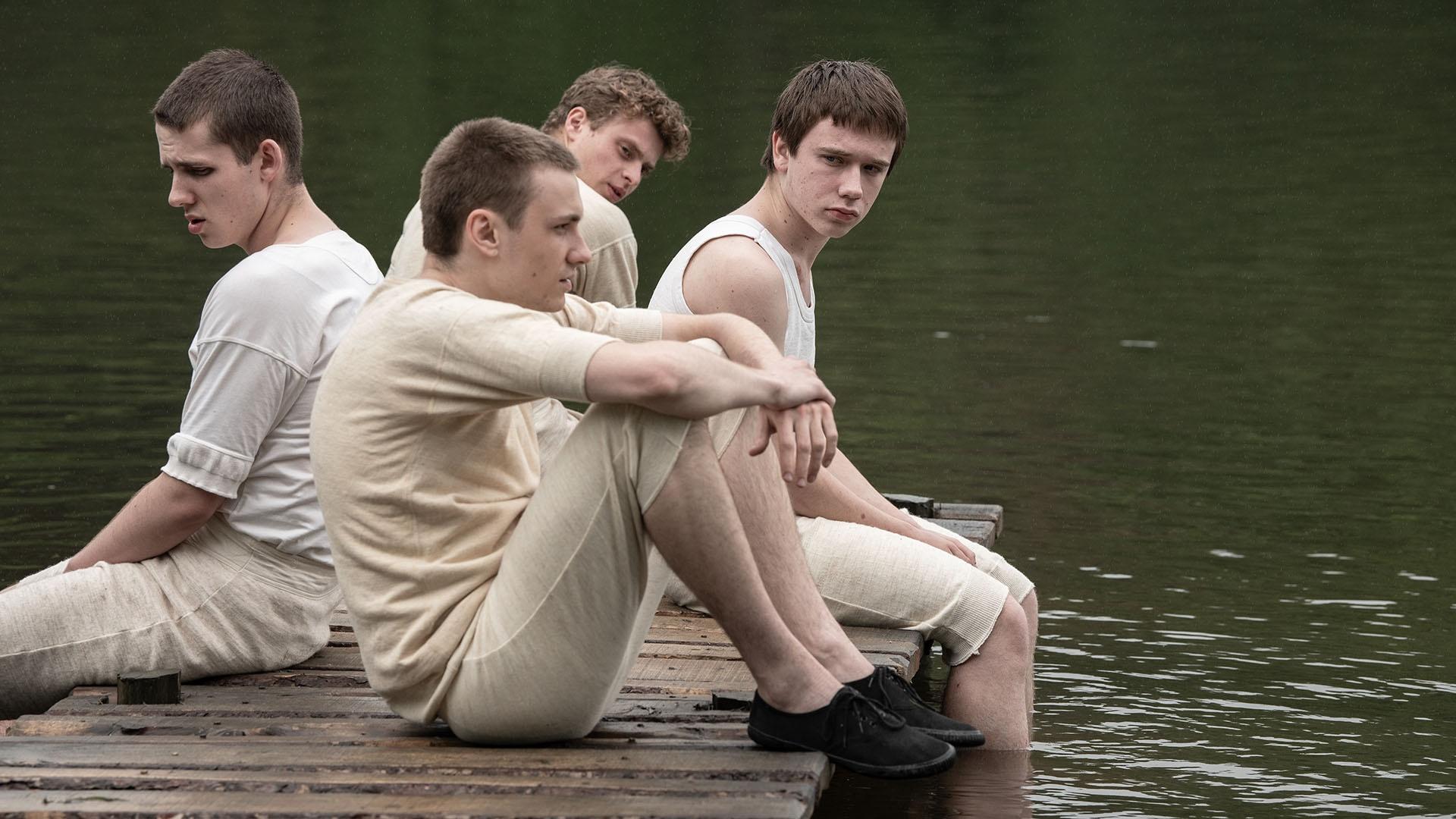 Four young boys sitting on a dock.