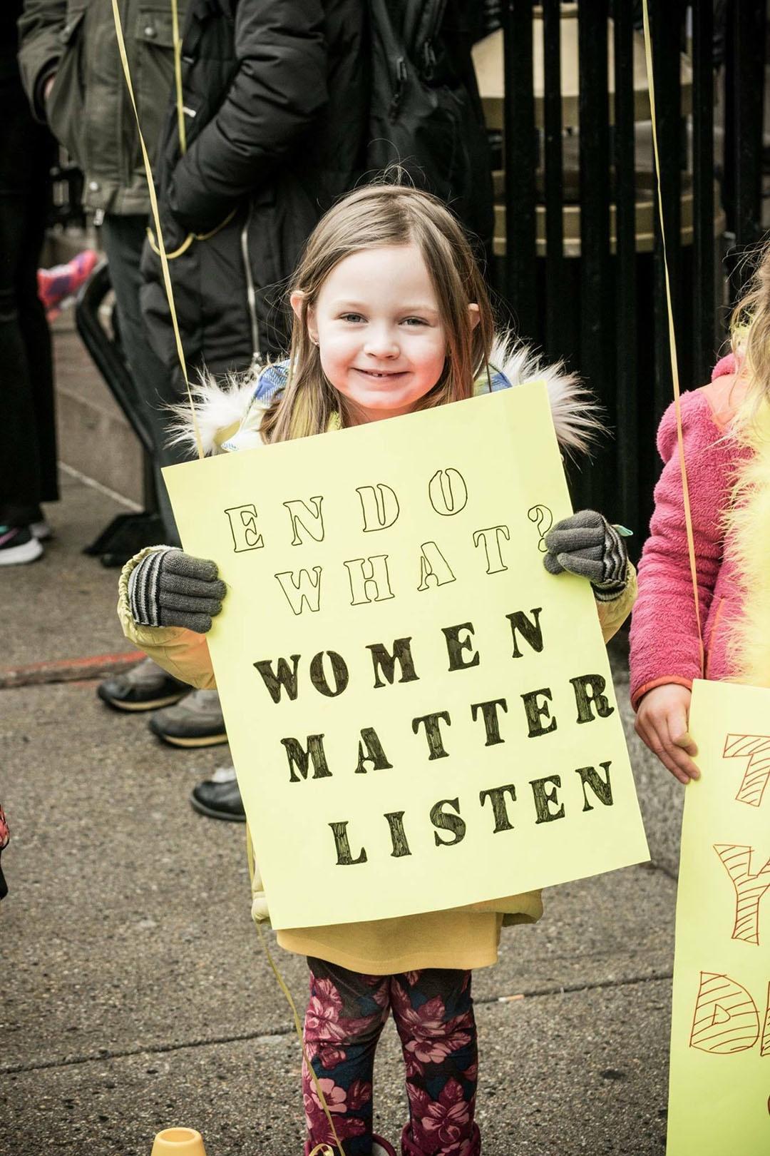 Maya Abrea holds a sign reading "Endo What? Women matter. Listen."