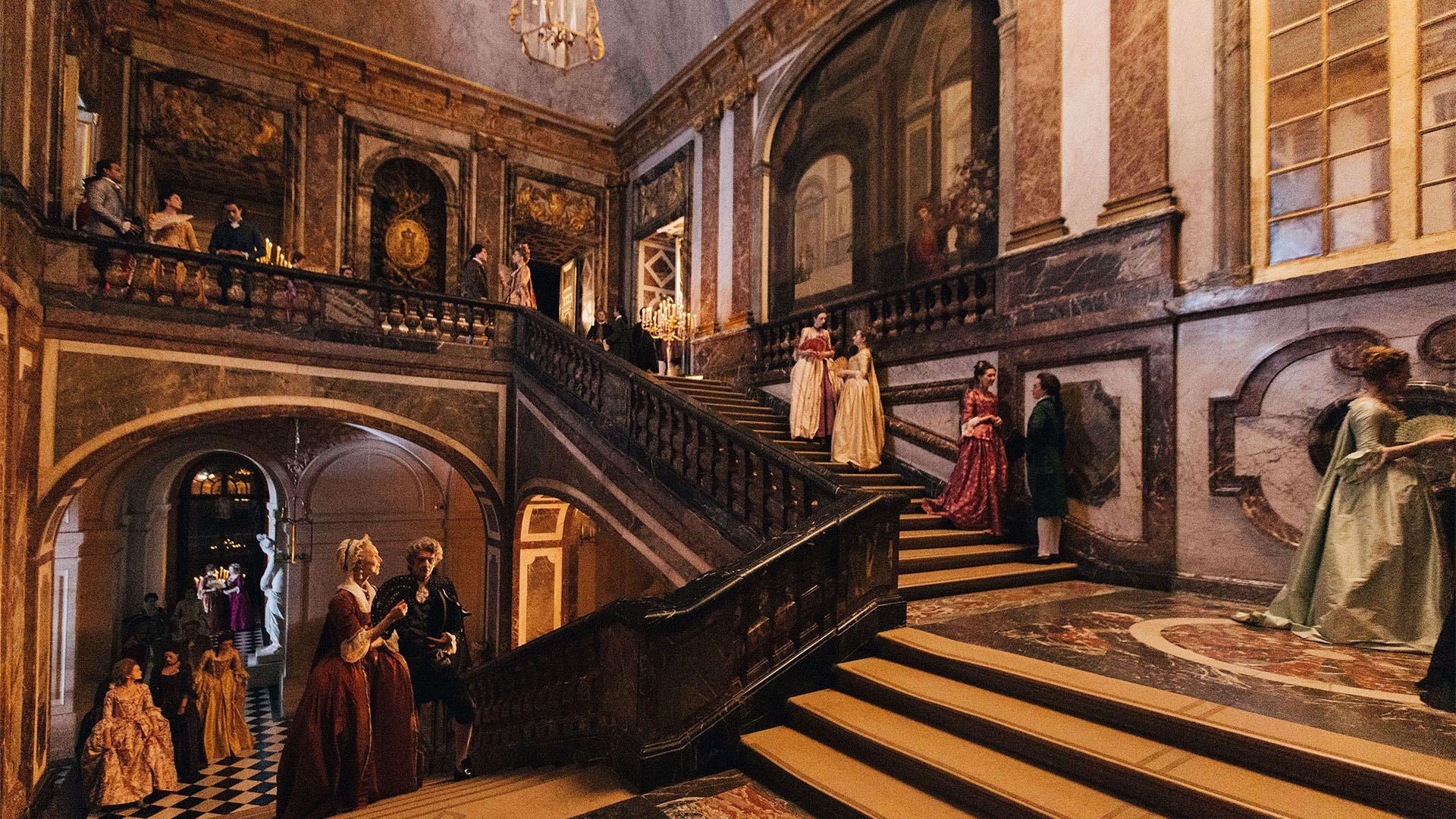 Image of members of the Court walking through the Palace of Versailles.