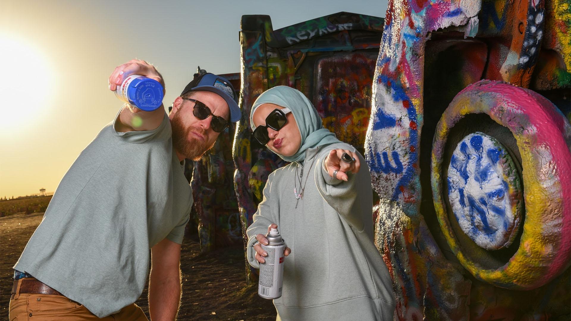 Sebastian Robins and Mona Haydar at the Cadillac Ranch with cans of spray paint.