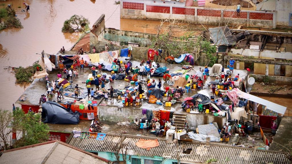 People gather on the roof of a house submerged by floods in Buzi on March 20, 2019.