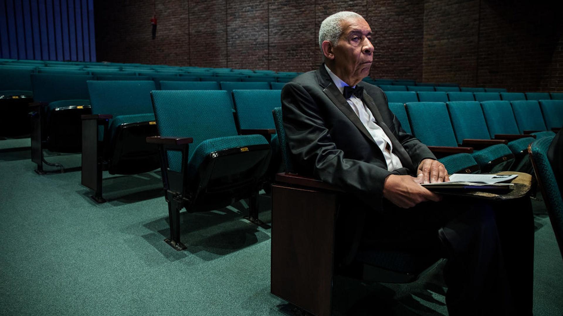 Norman Malone sitting in an empty auditorium, waiting.