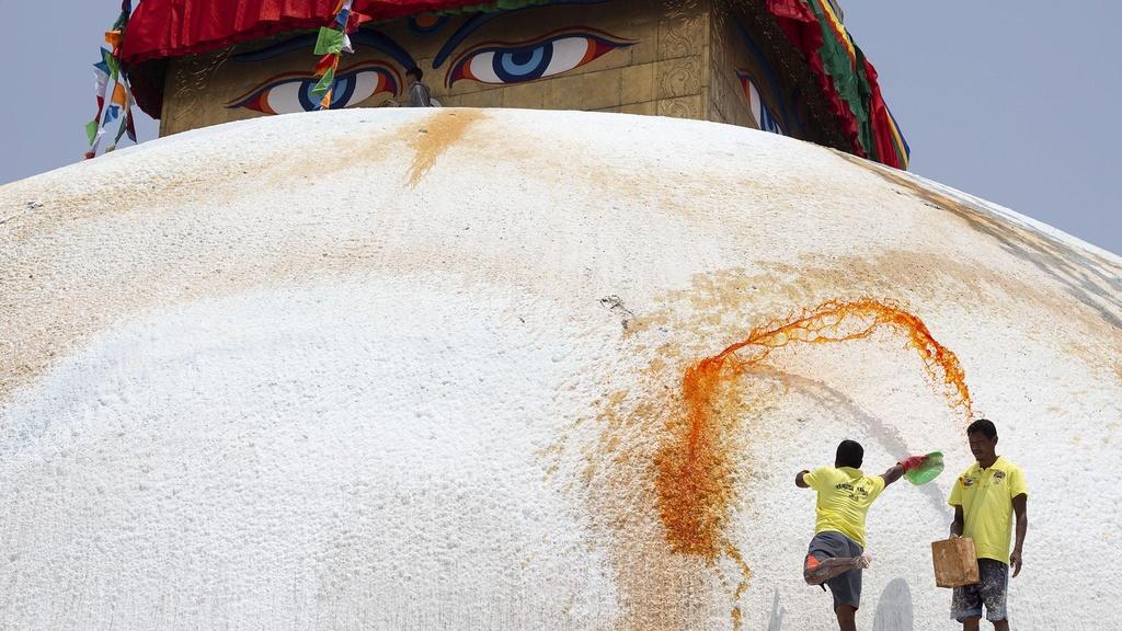 Two men paint the Boudhanath Stupa in Kathmandu, Nepal.