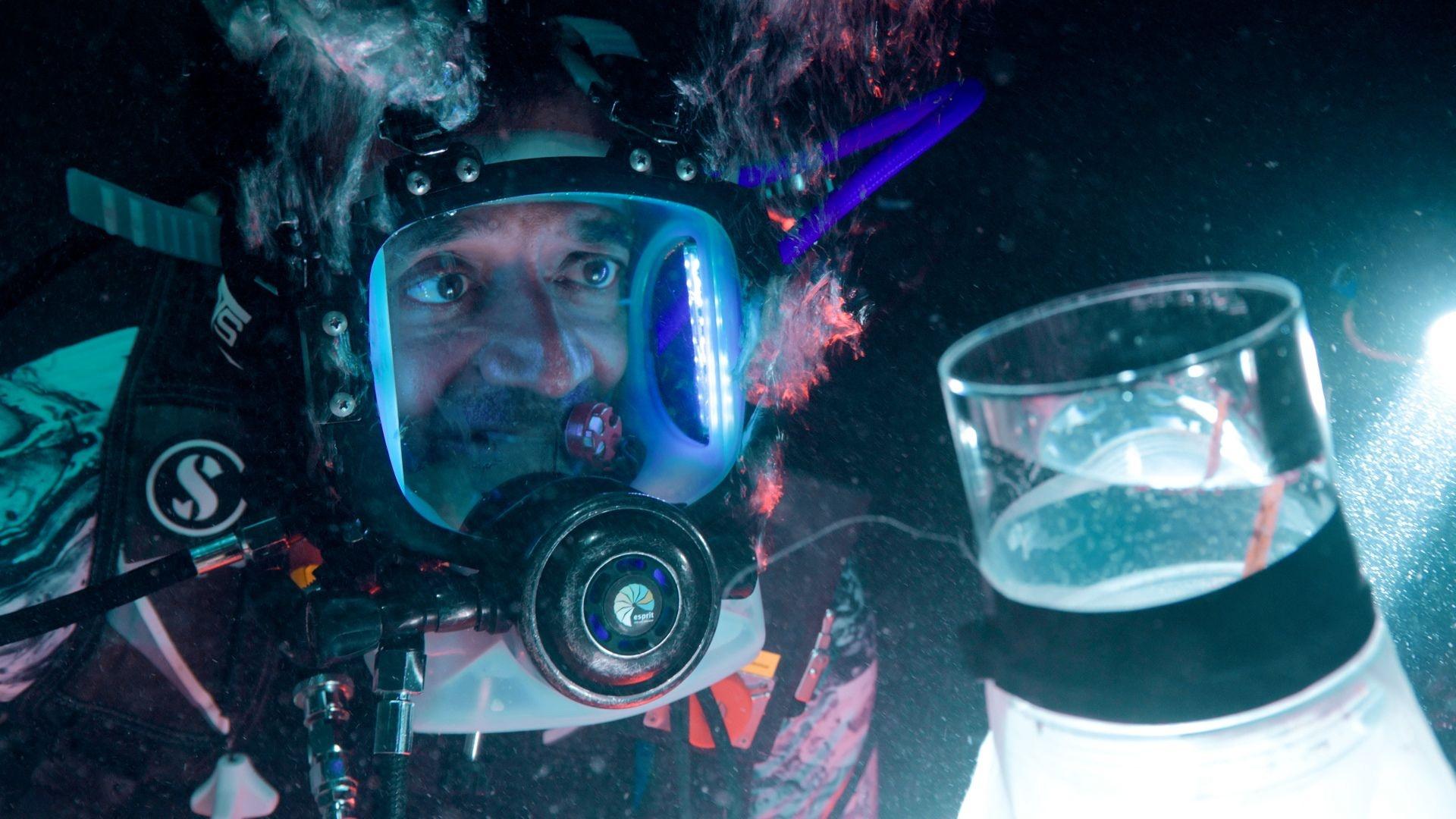 A close-up of Dr. M. Sanjayan looking at coral spawn caught in the net.