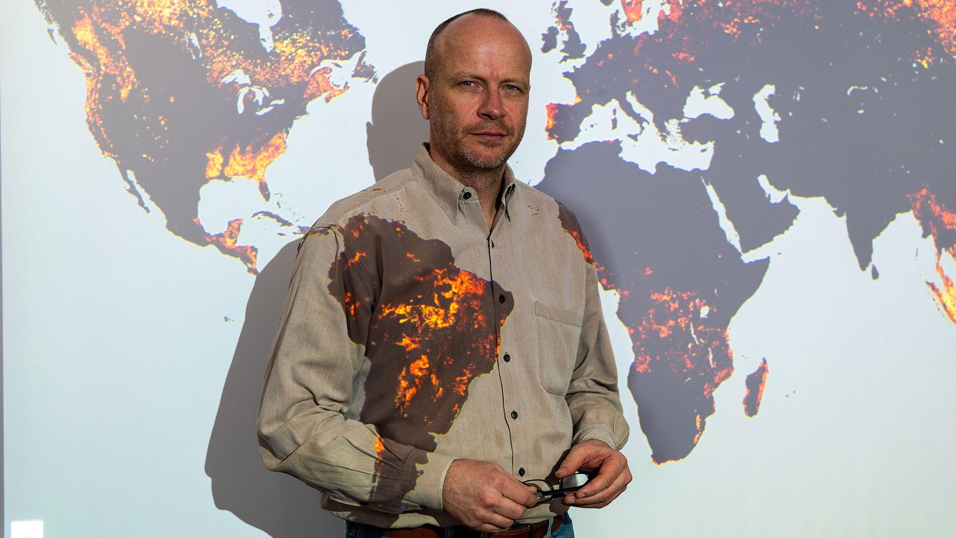 Prof. Matthew Hansen, Remote Sensing Scientist stands before a map projection