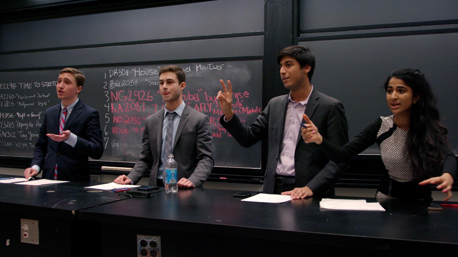 Anika and Jay stand alongside their two opponents during a final round of a competitive debate.