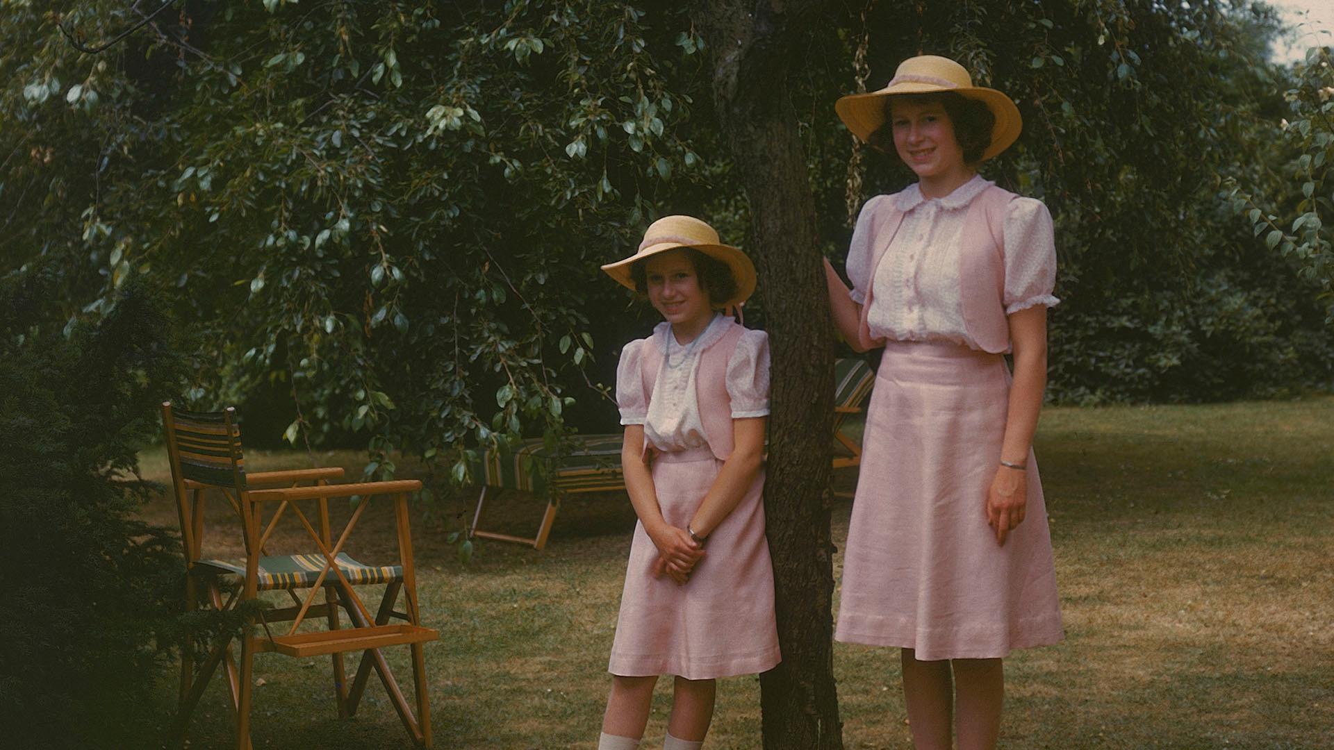 The Queen Mother and Princess Margaret standing by a tree.