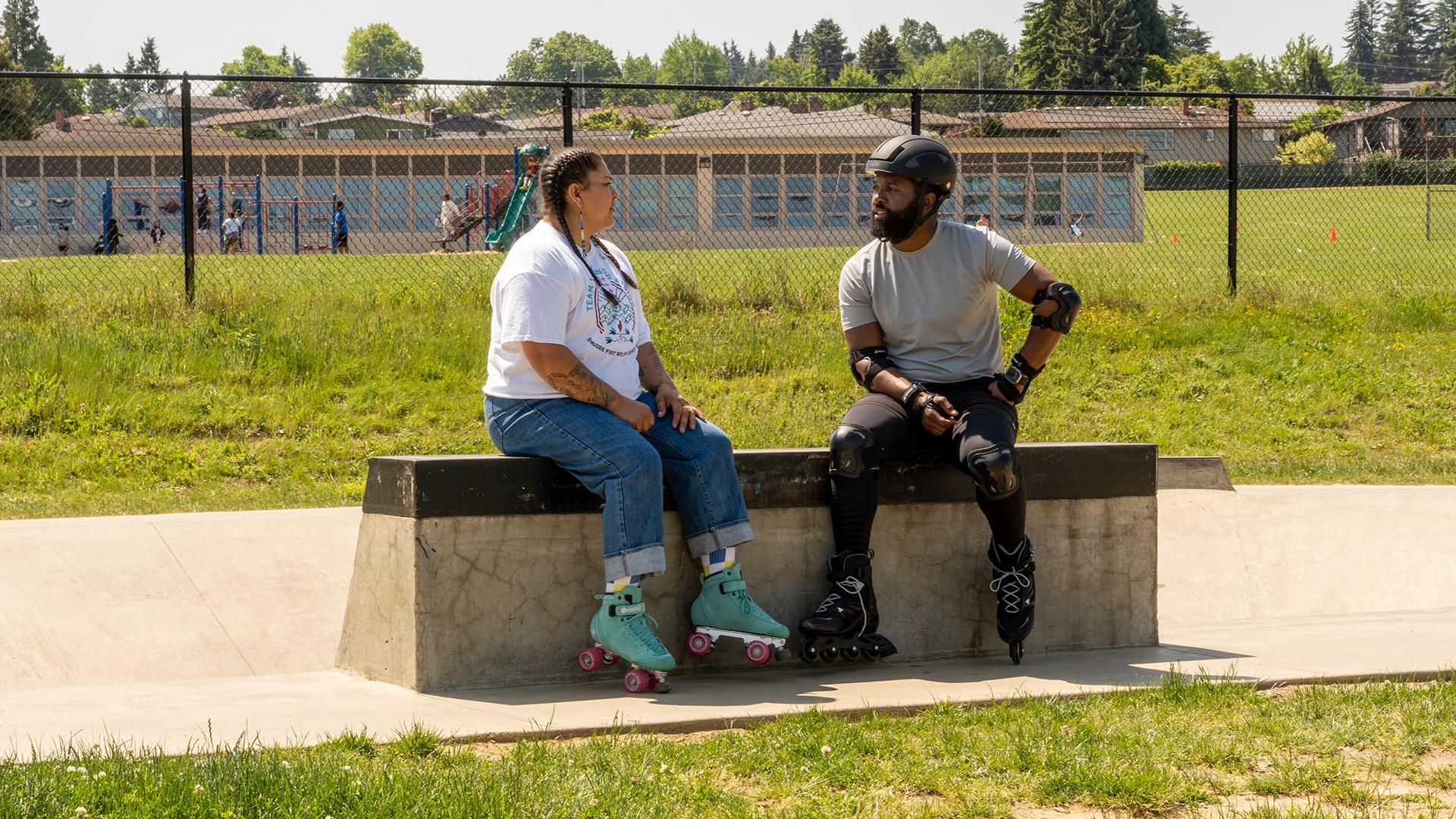 Two people sitting on a platform in roller skates