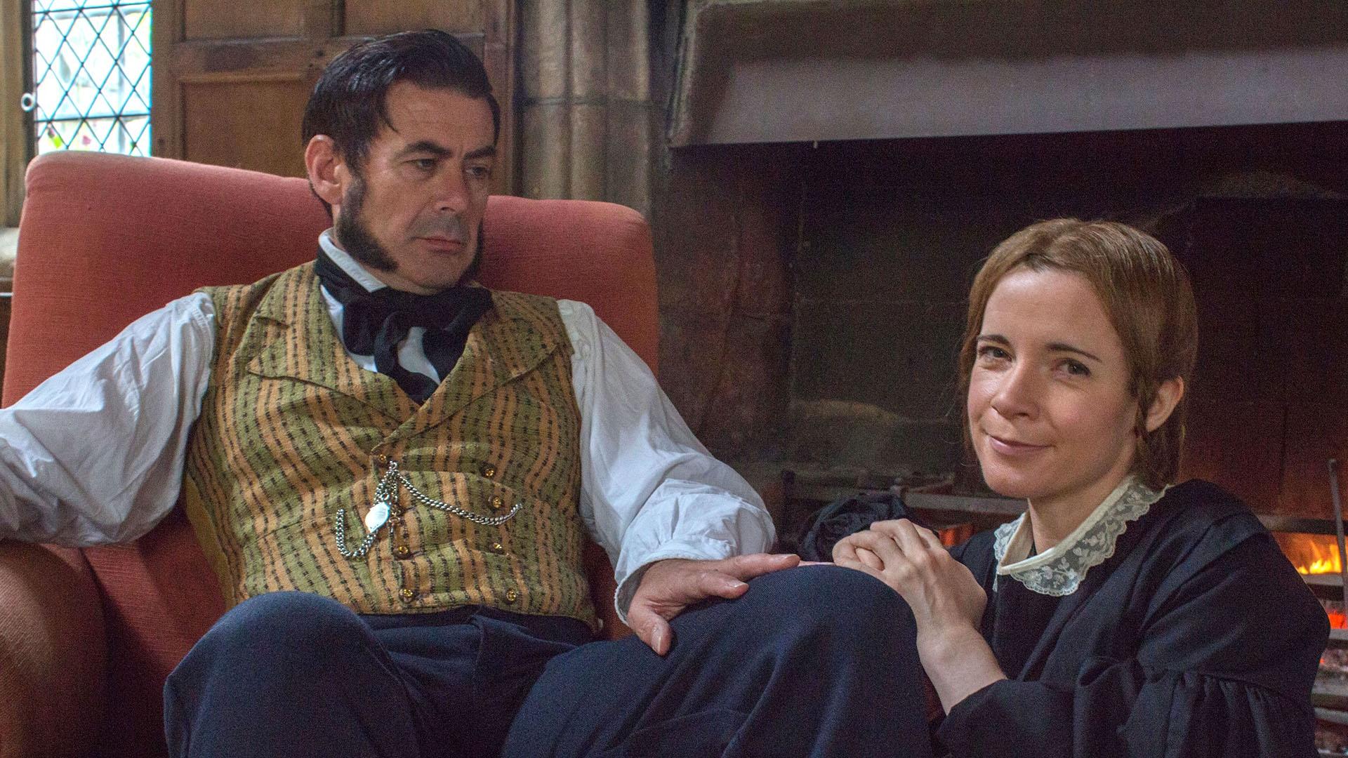 Lucy Worsley sitting with man dressed in period costume.