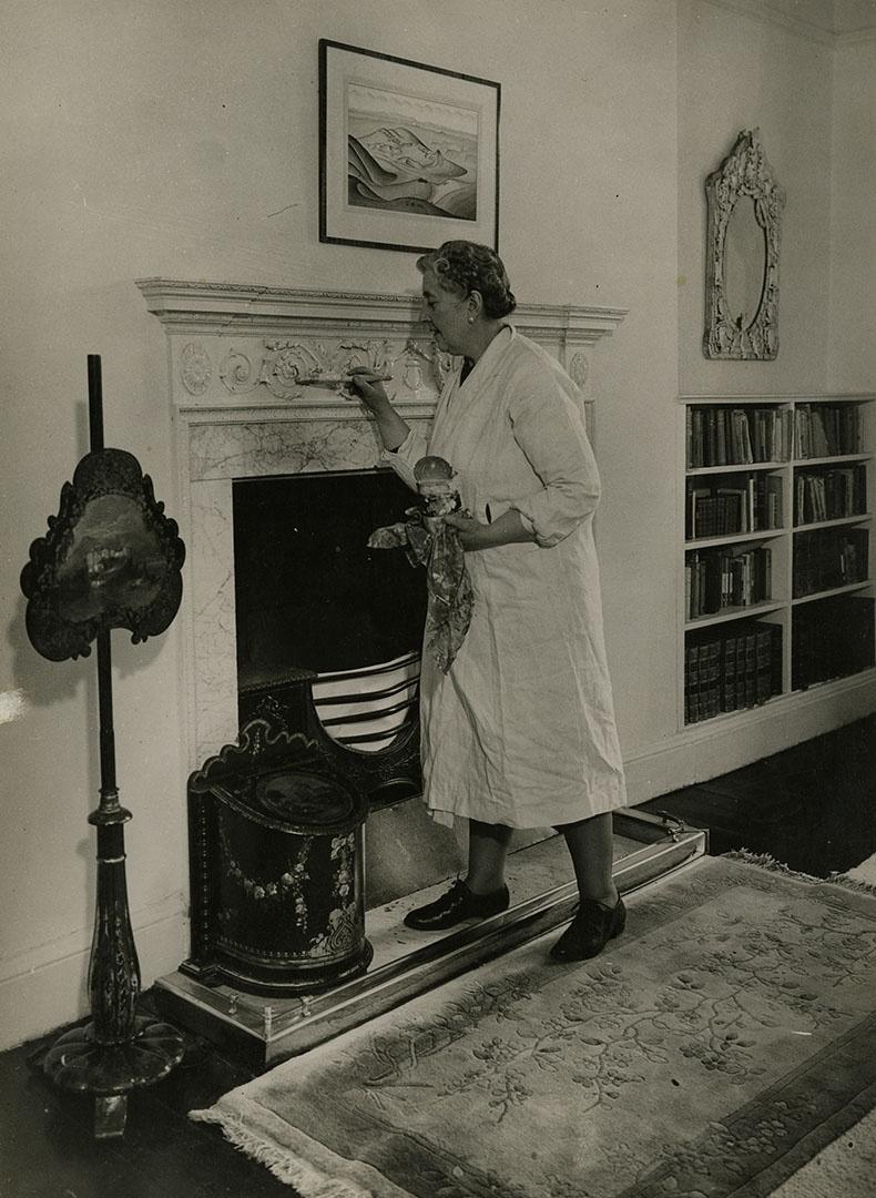 Image of Agatha Christie dusting for prints in a living room.