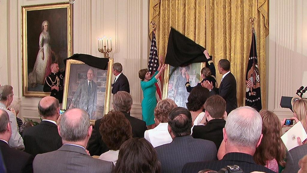 Laura and George Bush unveiling their portraits in the East Room alongside President Obama.
