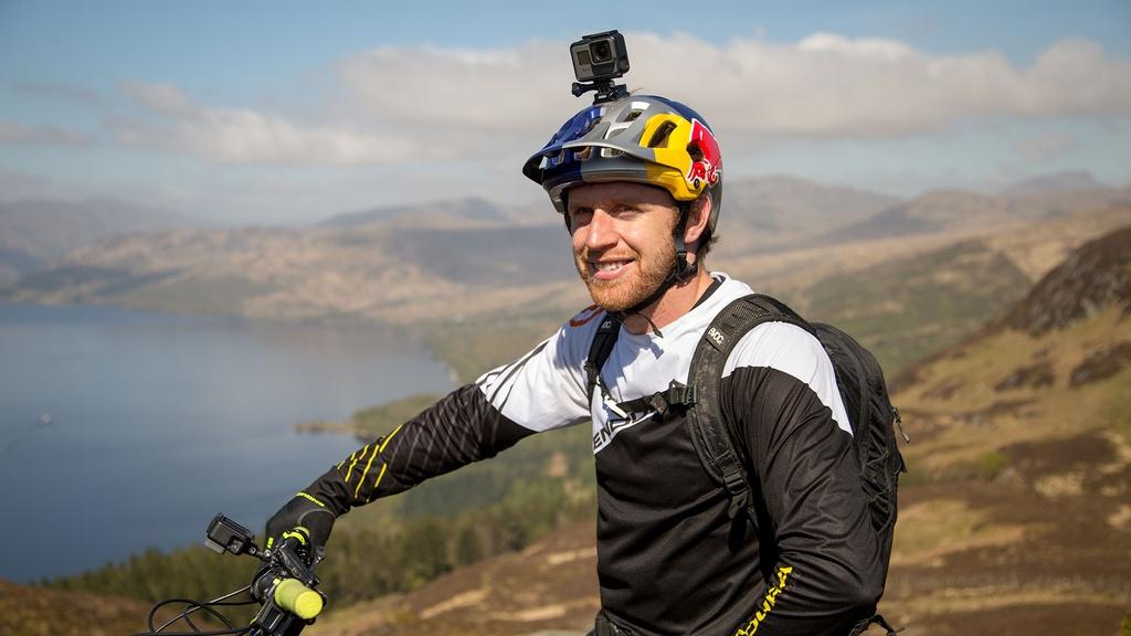 Pro-rider, Danny MacAskill, sits on his bike on the edge of Ben A’an mountain in Scotland.