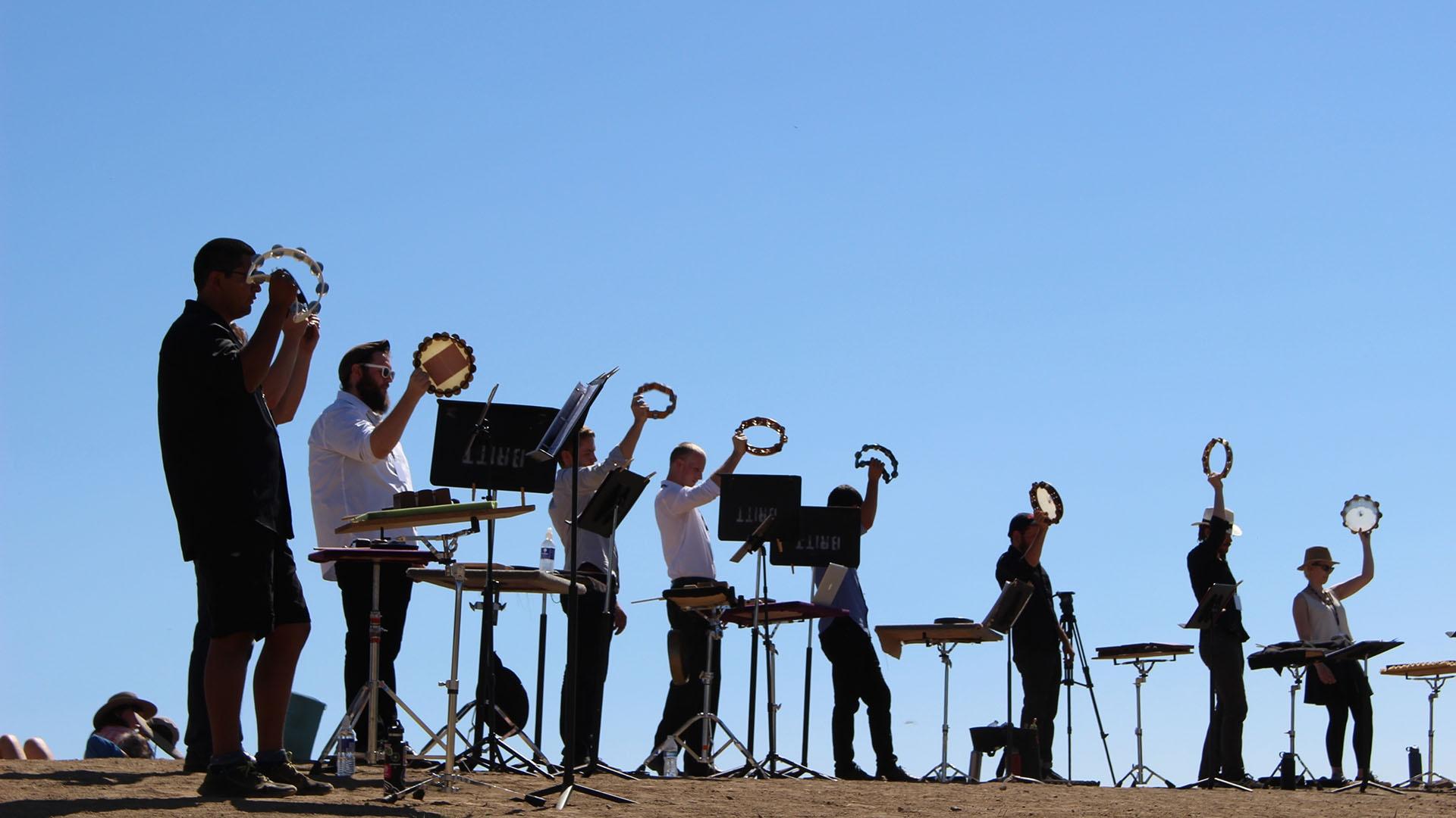 Tambourine players perform “Natural History” at the edge of Crater Lake