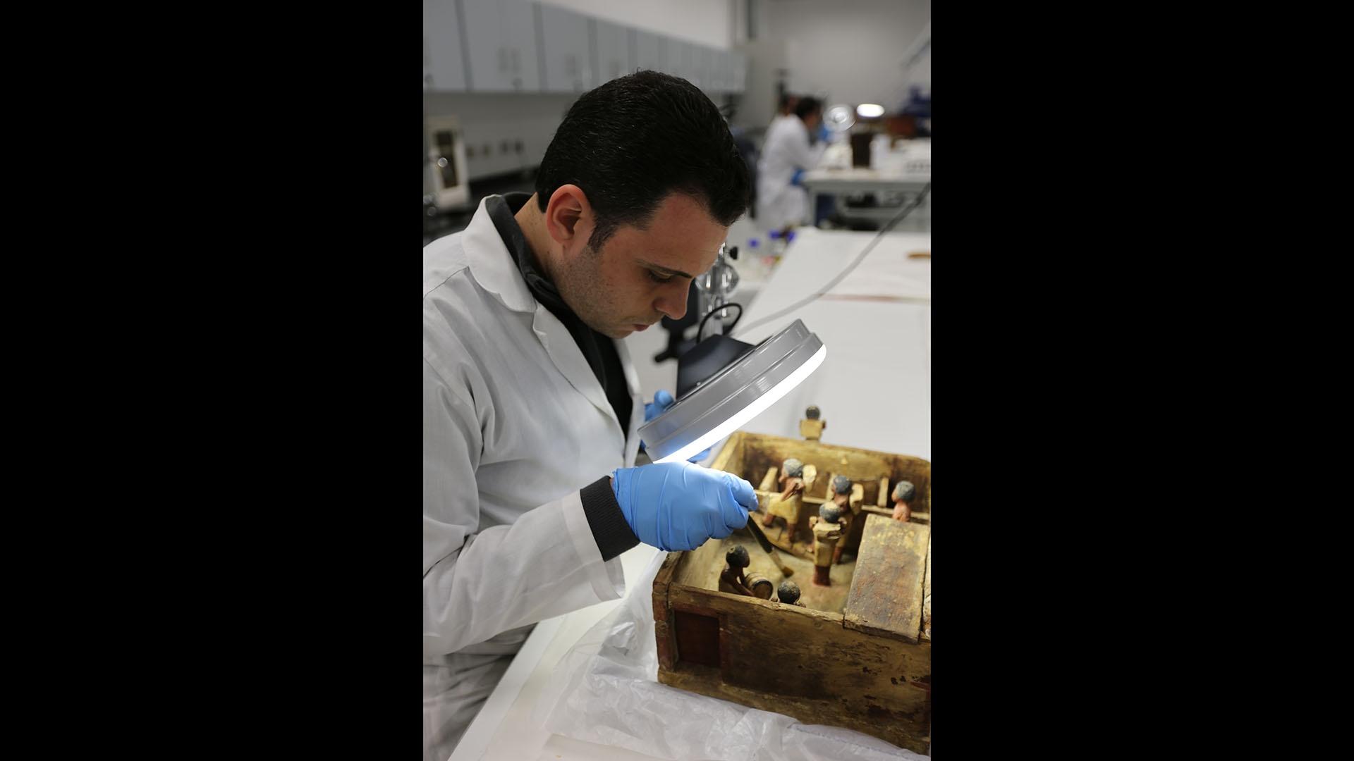 Conservationist at the GEM lab working on a wooden model.
