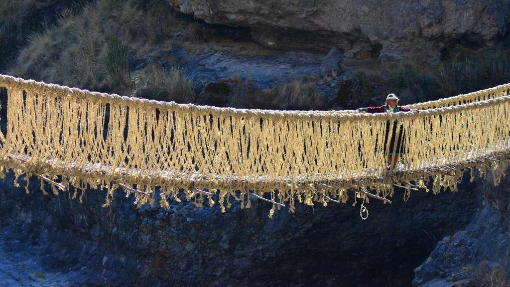 An elderly villager crosses the Q'eswachaka rope bridge in the Peruvian Andes.