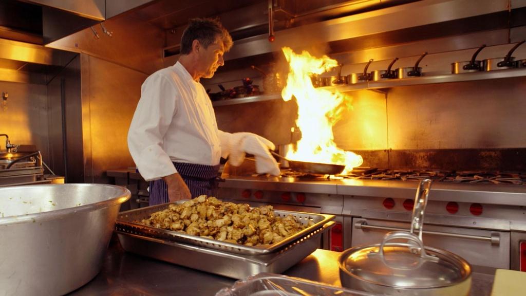 White House chef over stove with burning skillet.