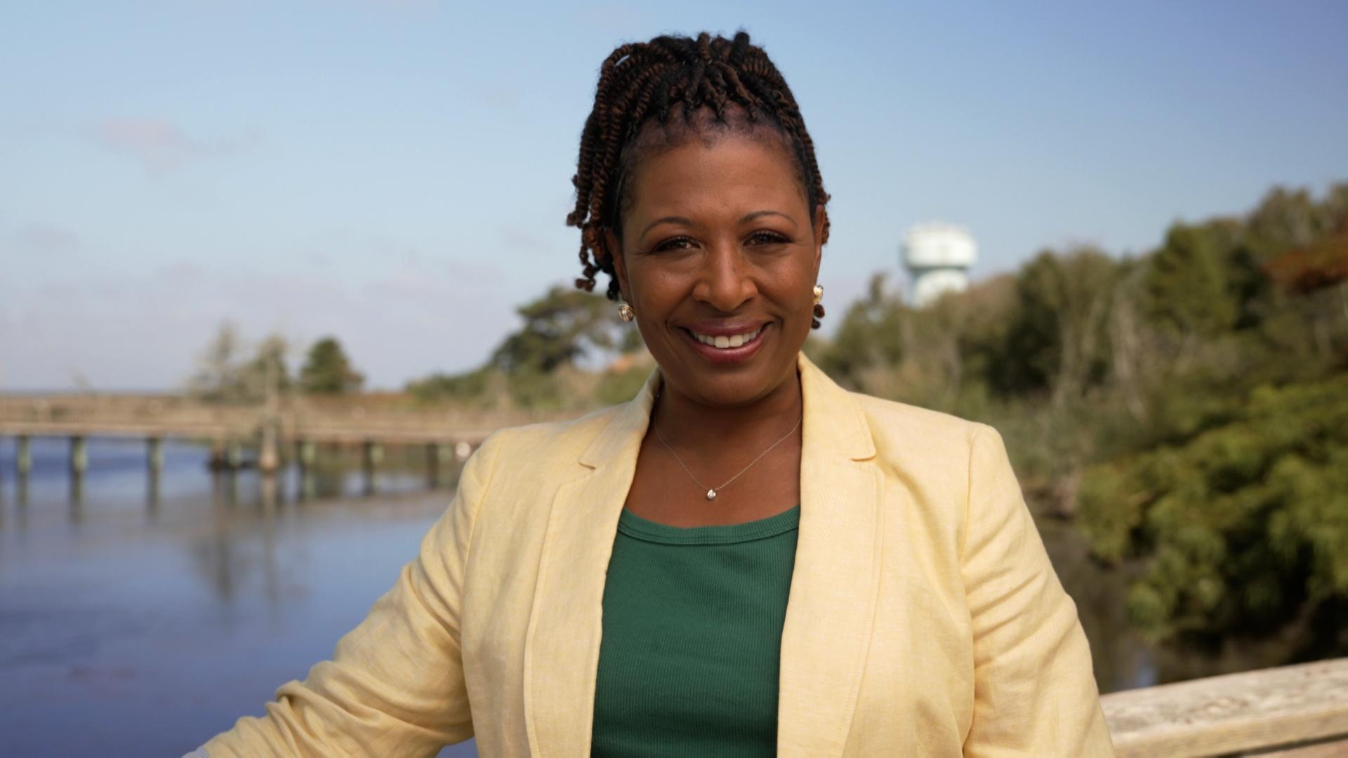 Host of NC Weekend Deborah Holt Noel in front of a pier in Duck, NC.