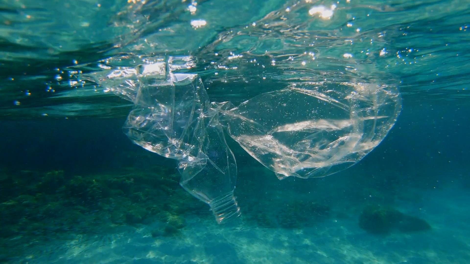 Plastic trash in clear blue water.