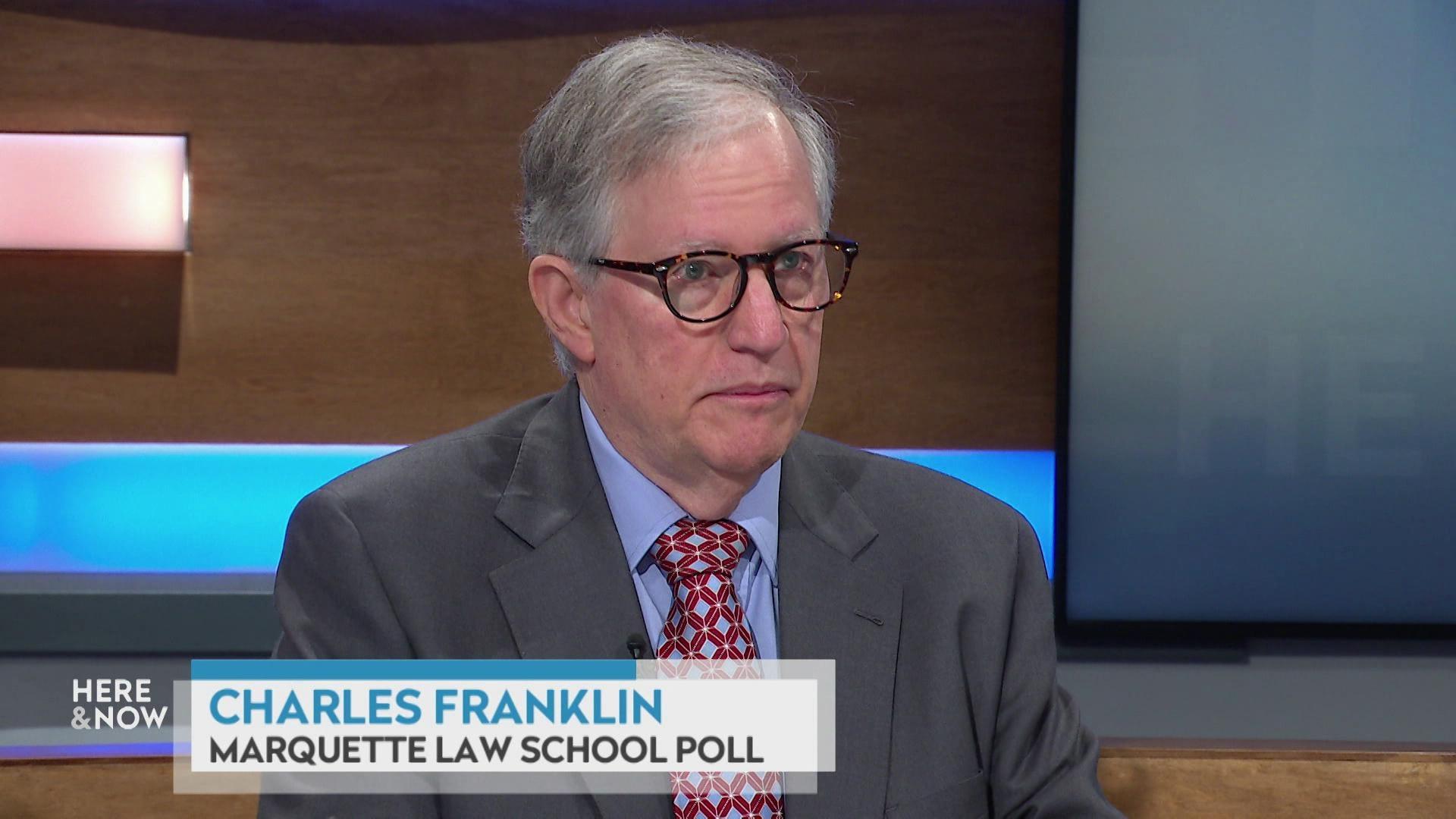 A still image shows Charles Franklin seated at the 'Here & Now' set featuring wood paneling, with a graphic at bottom reading 'Charles Franklin' and 'Marquette Law School Poll.' A still image shows Charles Franklin seated at the 'Here & Now' set featuring wood paneling, with a graphic at bottom reading 'Charles Franklin' and 'Marquette Law School Poll.'