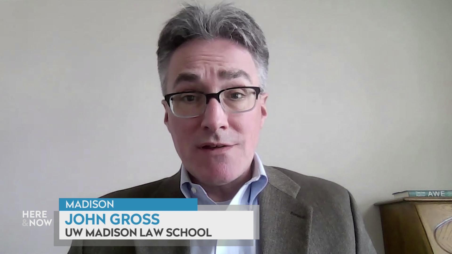 A still image from a video shows John Gross sitting with a graphic at bottom reading Madison,' 'John Gross' and 'UW Madison Law School.'