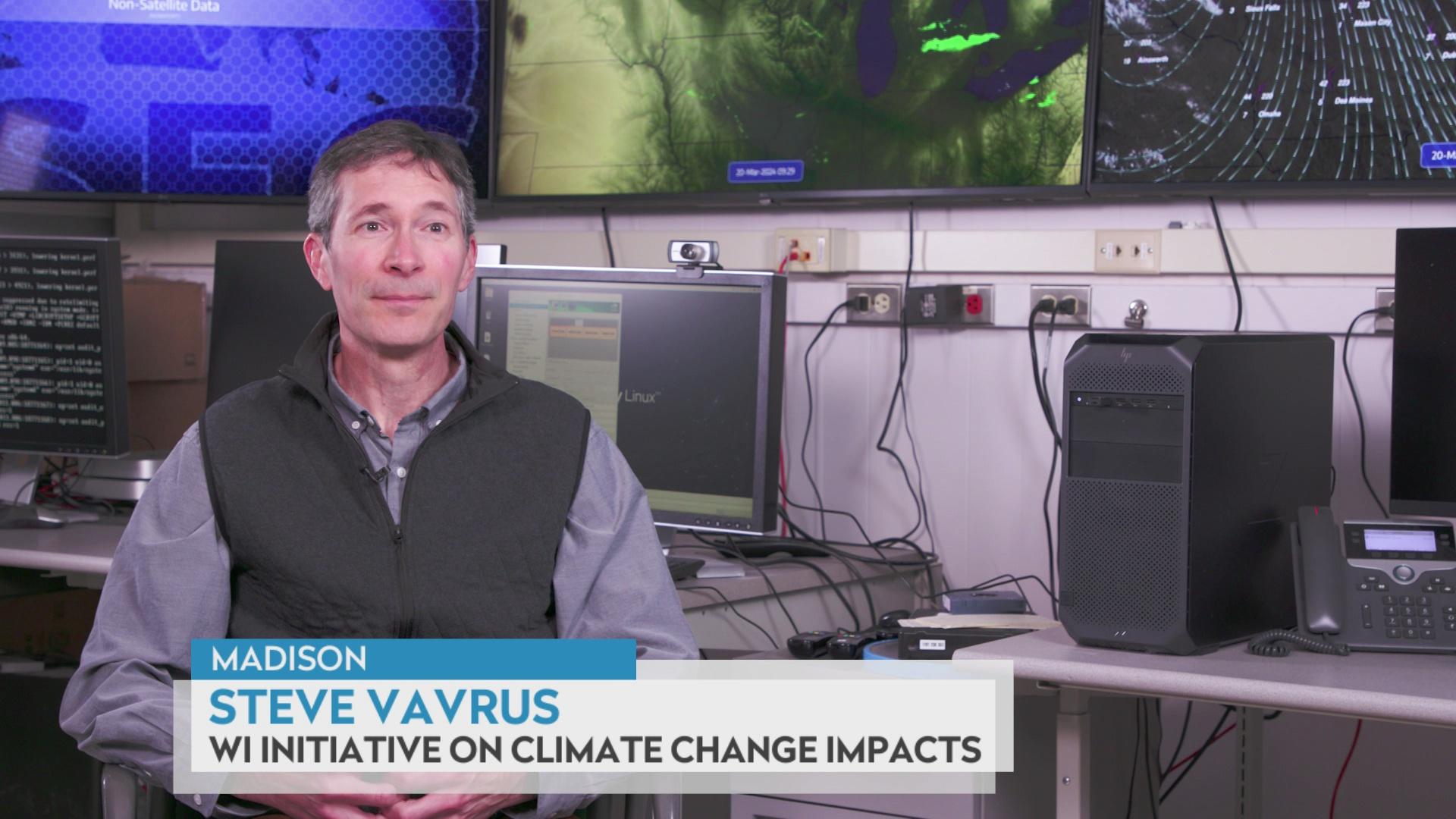 Steve Vavrus sits in a climatology office in front of weather models.