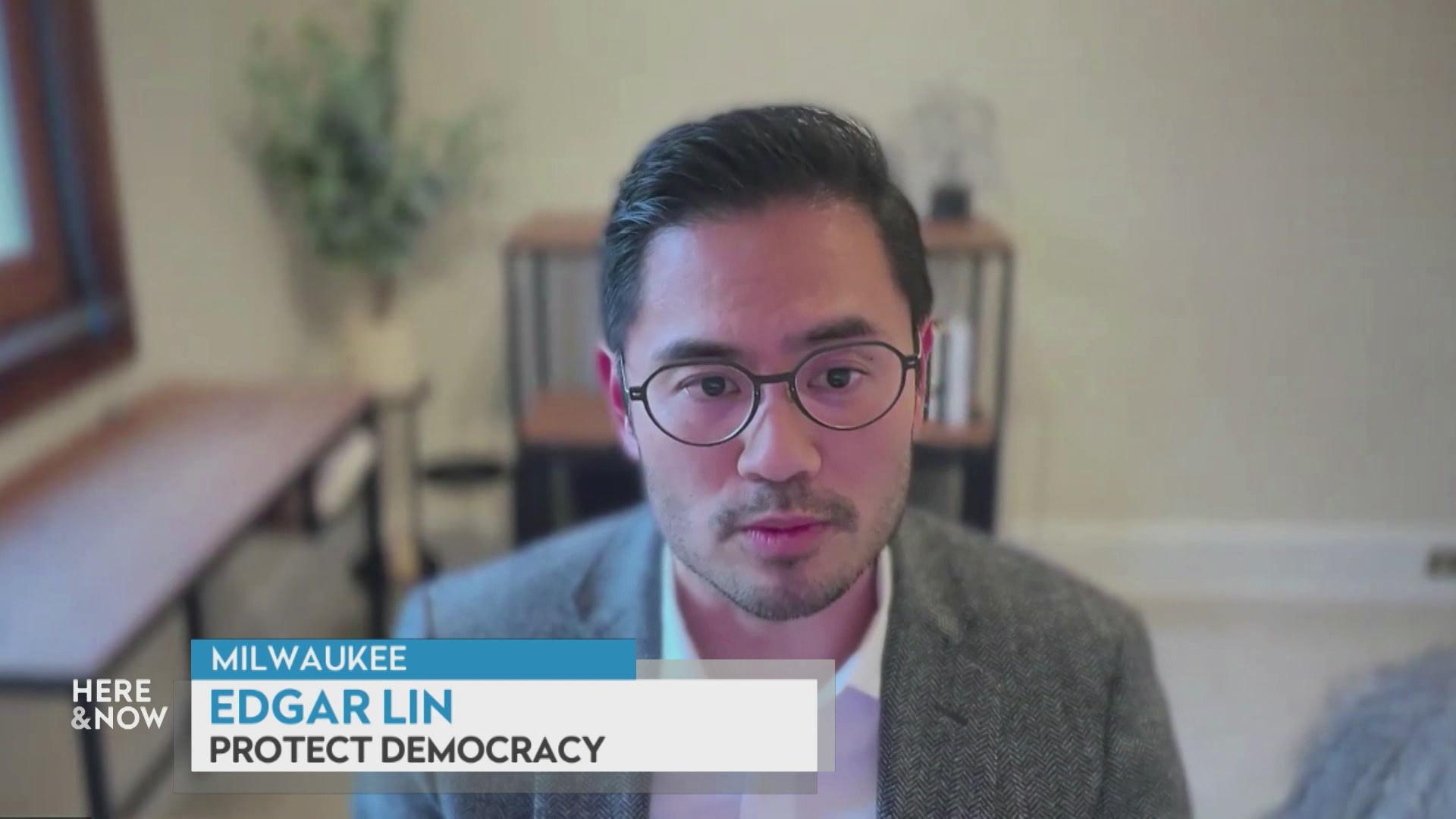 A still image from a video shows Edgar Lin  seated in front of a blurred background with a graphic at bottom reading 'Milwaukee,' 'Edgar Lin' and 'Protect Democracy.'