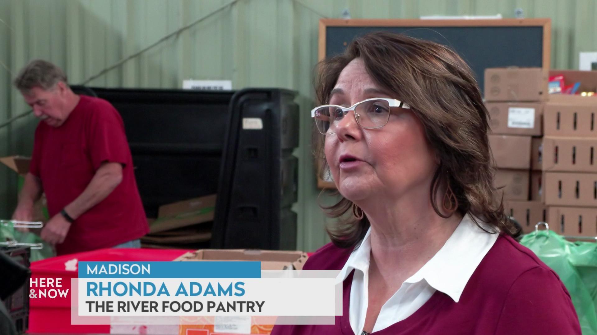A still image shows Rhonda Adams standing in a warehouse where workers are organizing food donations, with a graphic at the bottom that reads 'Madison,' 'Rhonda Adams' and 'The River Food Pantry.' A still image shows Rhonda Adams standing in a warehouse where workers are organizing food donations, with a graphic at the bottom that reads 'Madison,' 'Rhonda Adams' and 'The River Food Pantry.'