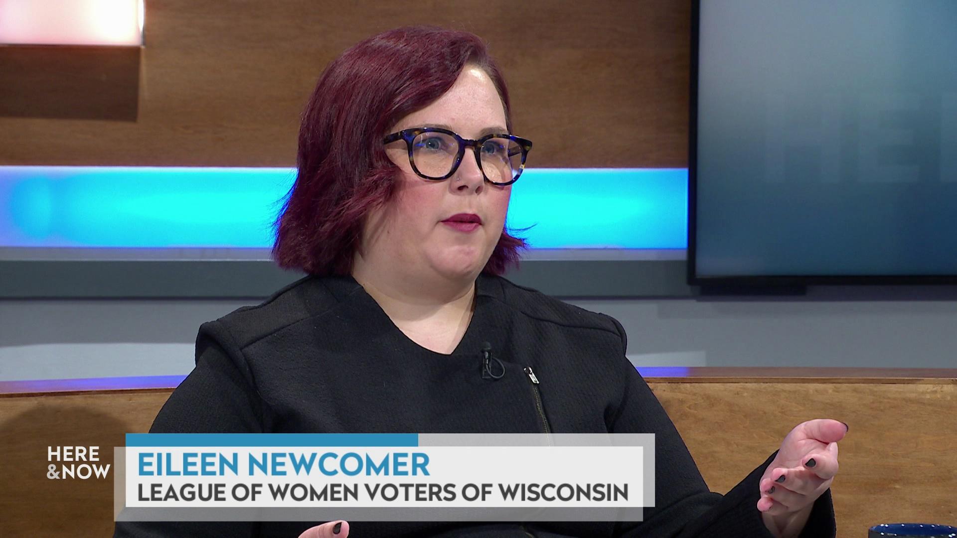 A still image shows Eileen Newcomer seated at the 'Here & Now' set featuring wood paneling, with a graphic at bottom reading 'Eileen Newcomer' and 'League of Women Voters of Wisconsin.'