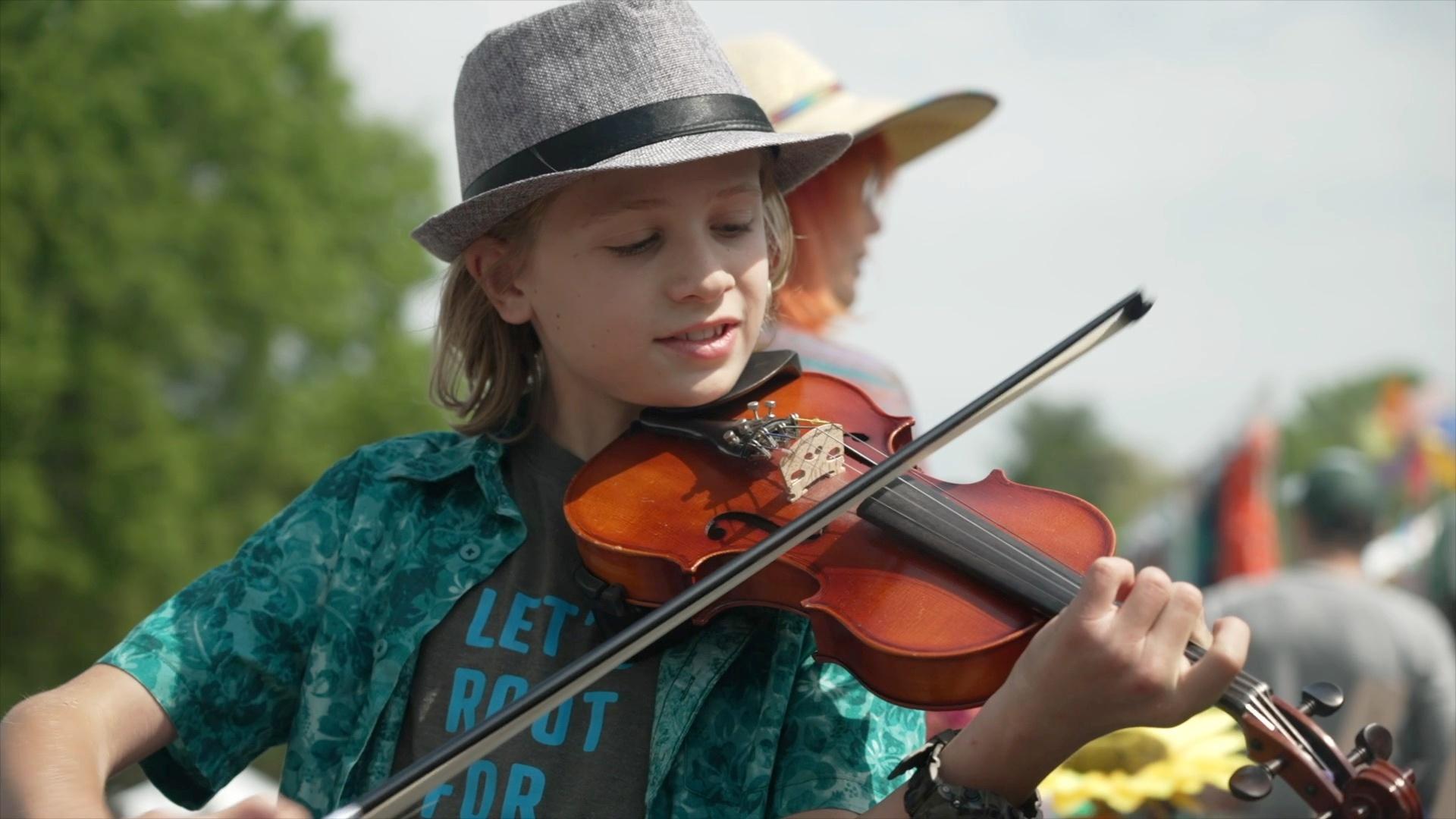 A child in a grey fedora playing the violin at MerleFest