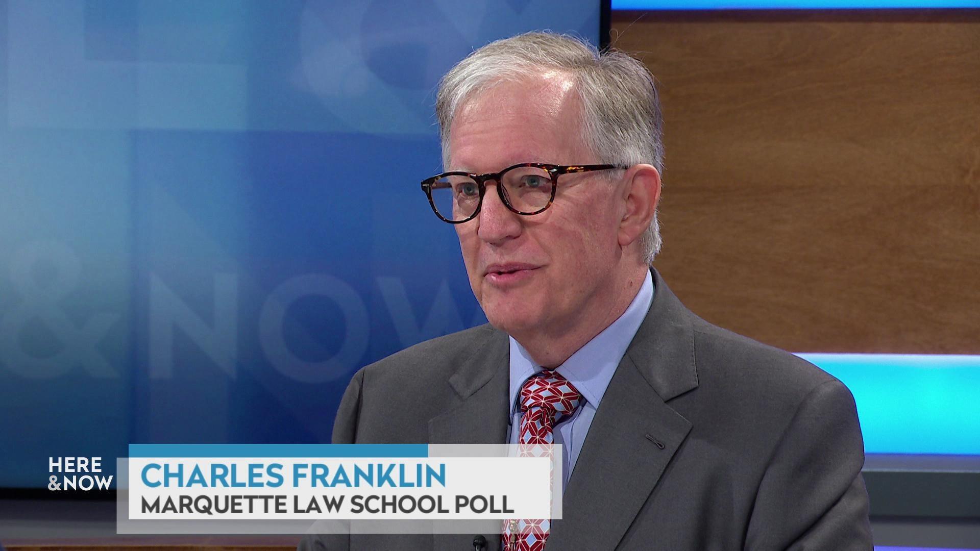 A still image shows Charles Franklin seated at the 'Here & Now' set featuring wood paneling, with a graphic at bottom reading 'Charles Franklin' and 'Marquette Law School Poll.'' A still image shows Charles Franklin seated at the 'Here & Now' set featuring wood paneling, with a graphic at bottom reading 'Charles Franklin' and 'Marquette Law School Poll.''