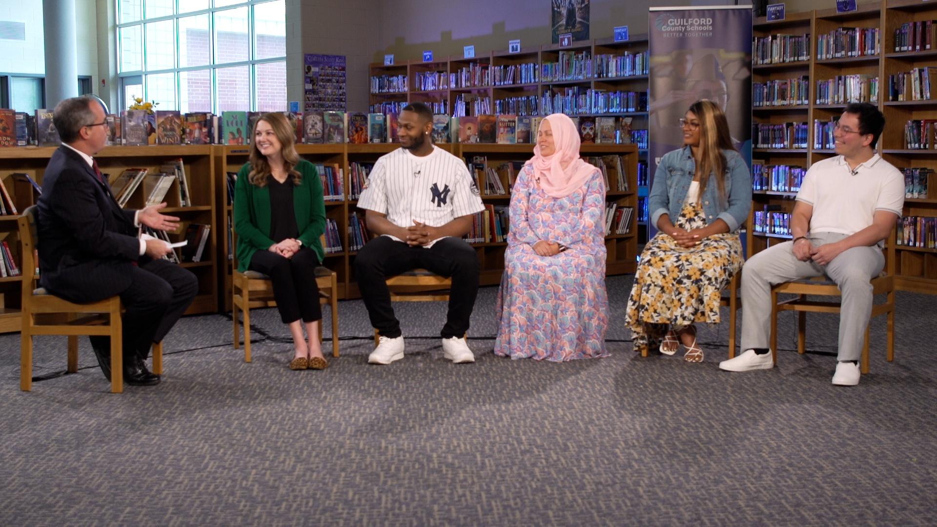 Host Kelly McCullen and panel of educators seated in a semicircle in a library