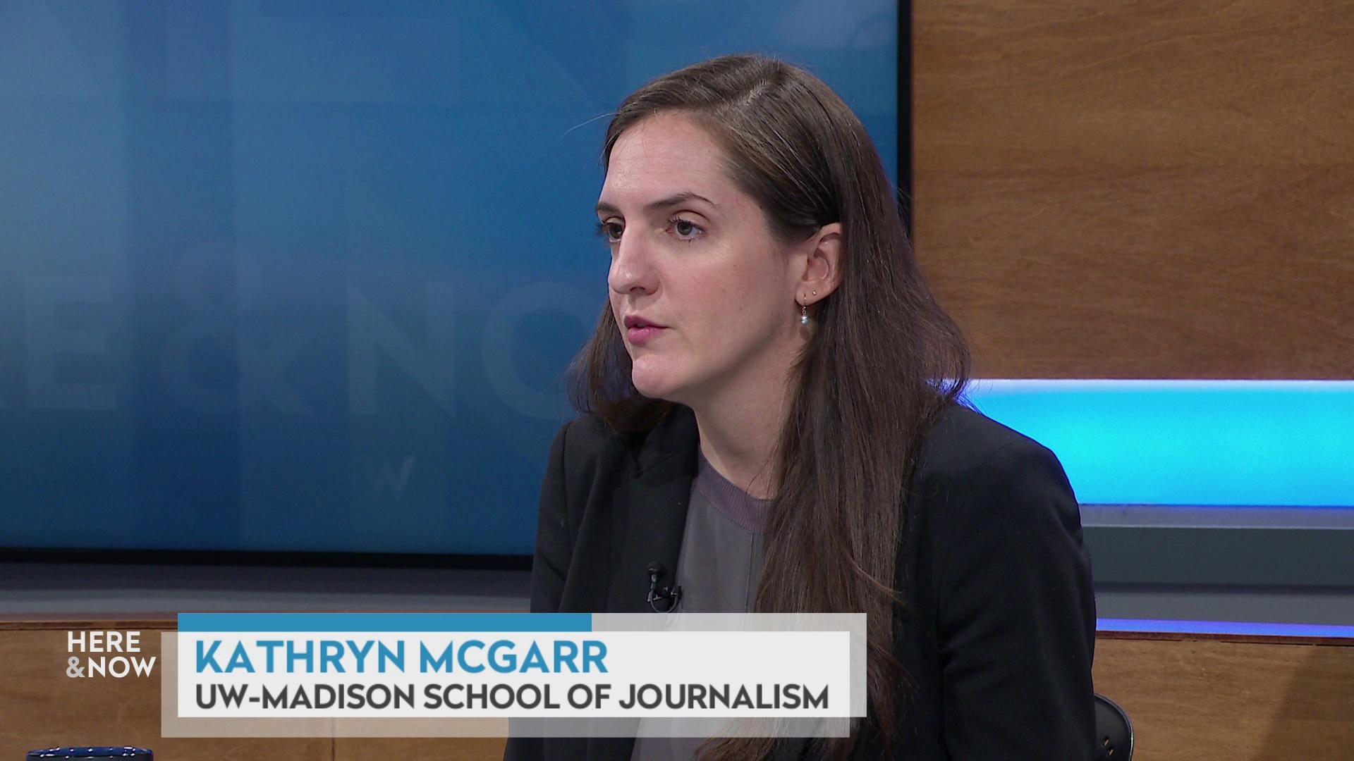 A still image shows Kathryn McGarr seated at the 'Here & Now' set featuring wood paneling, with a graphic at bottom reading 'Kathryn McGarr' and 'UW-Madison School of Journalism.'