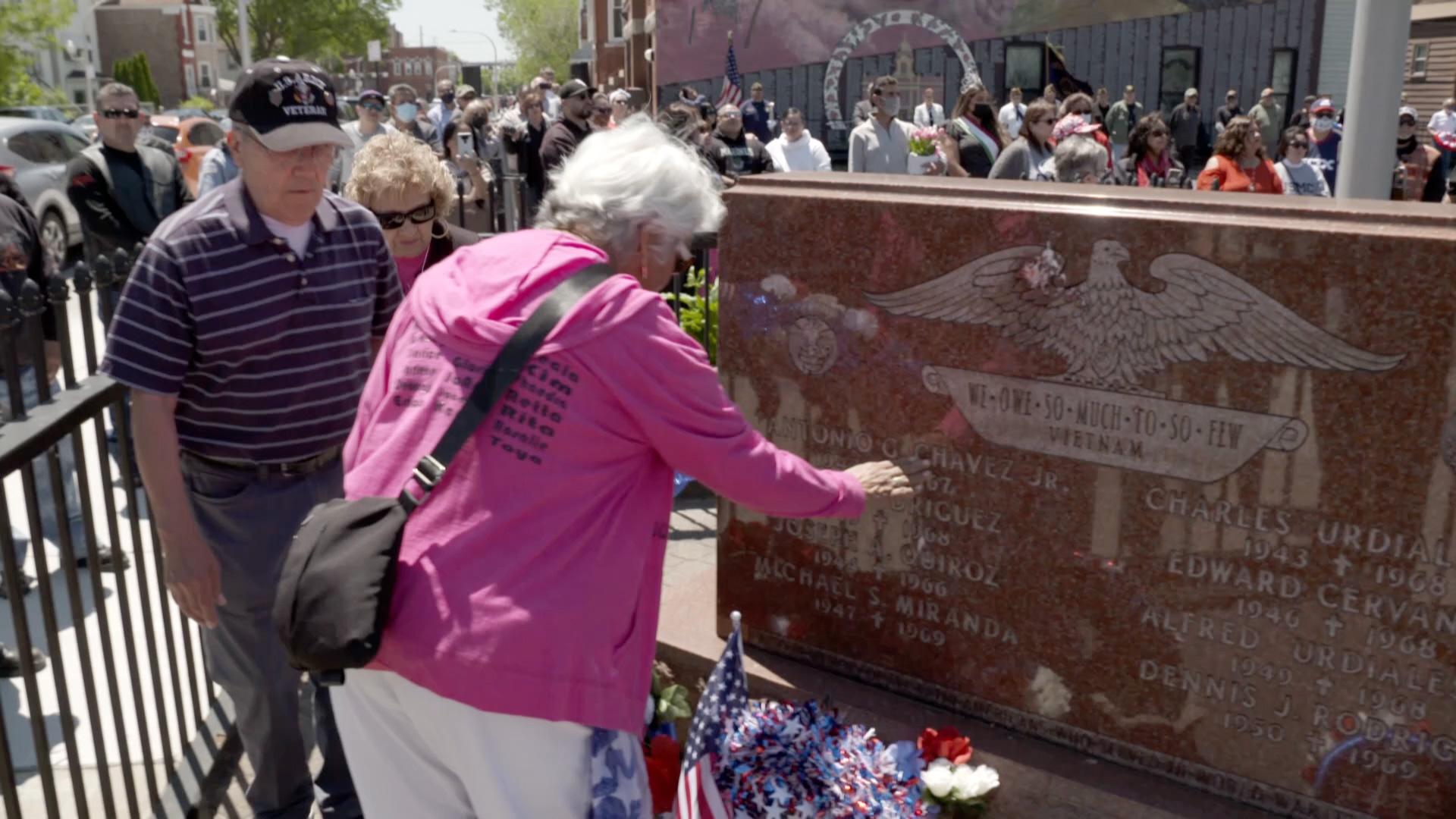 Woman touching Vietnam memorial with crowd of people around and in background