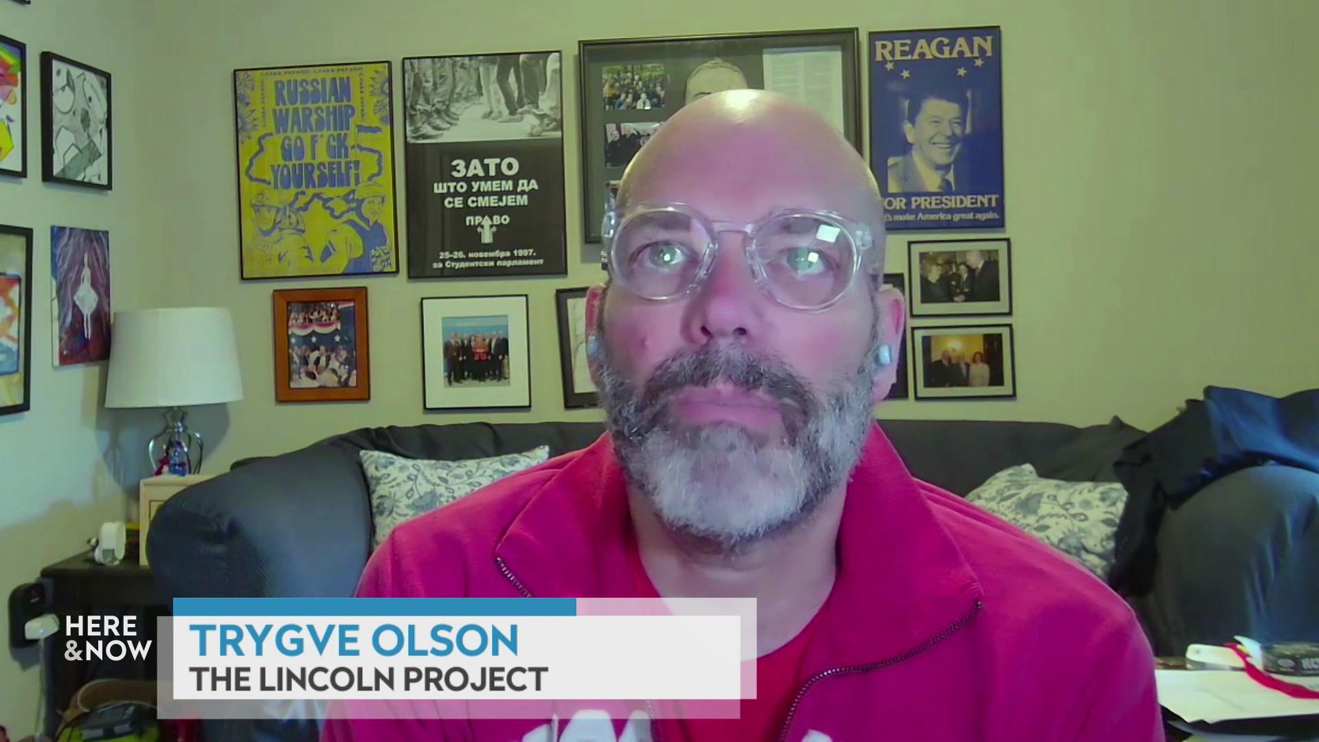 A still image from a video shows Trygve Olson seated in front of a couch, lamp and framed artwork on the wall with a graphic at bottom reading 'Trygve Olson' and 'The Lincoln Project.'