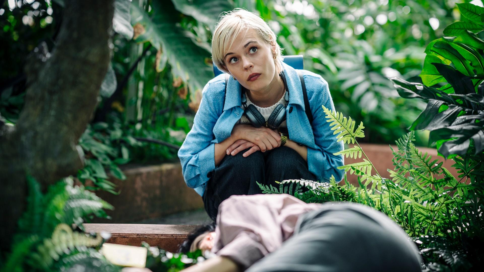 Ella Maisy Purvis as Patience Evans crouched down in a garden with a dead body laying in front of her.