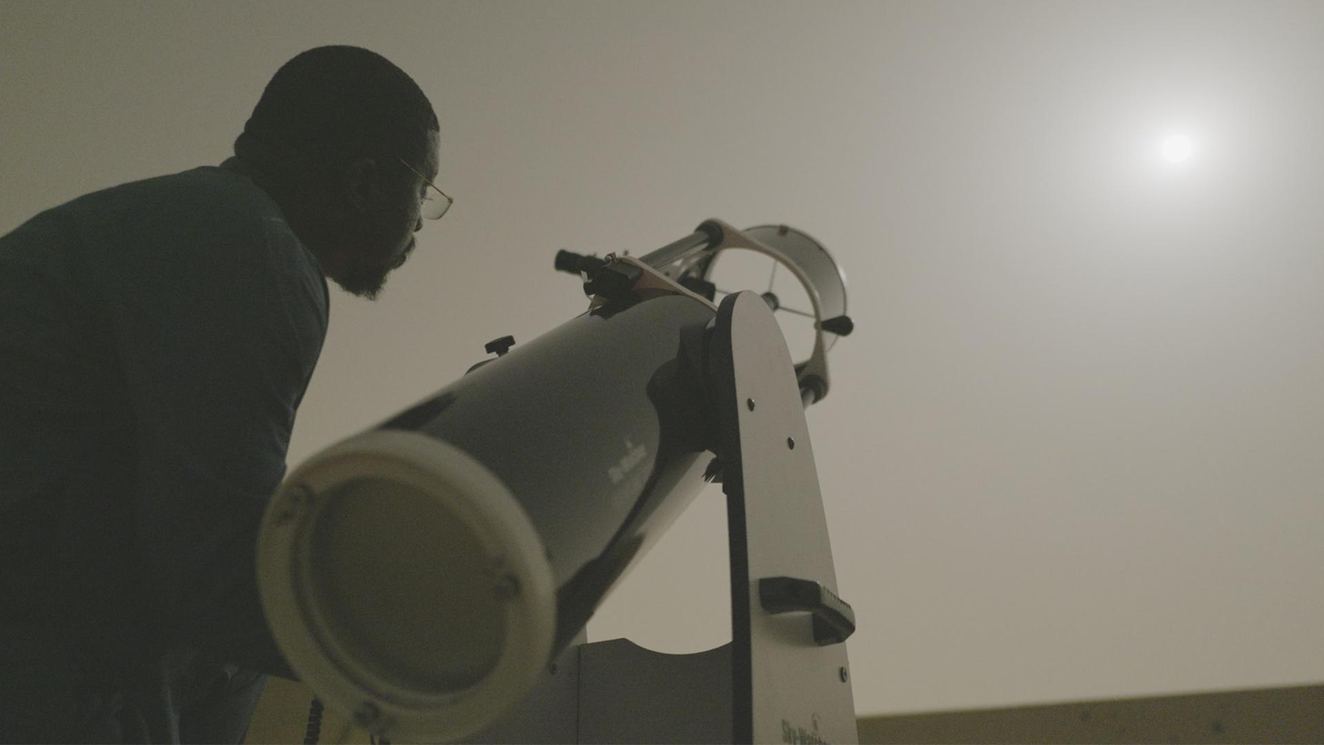 a man with a telescope looking at the stars
