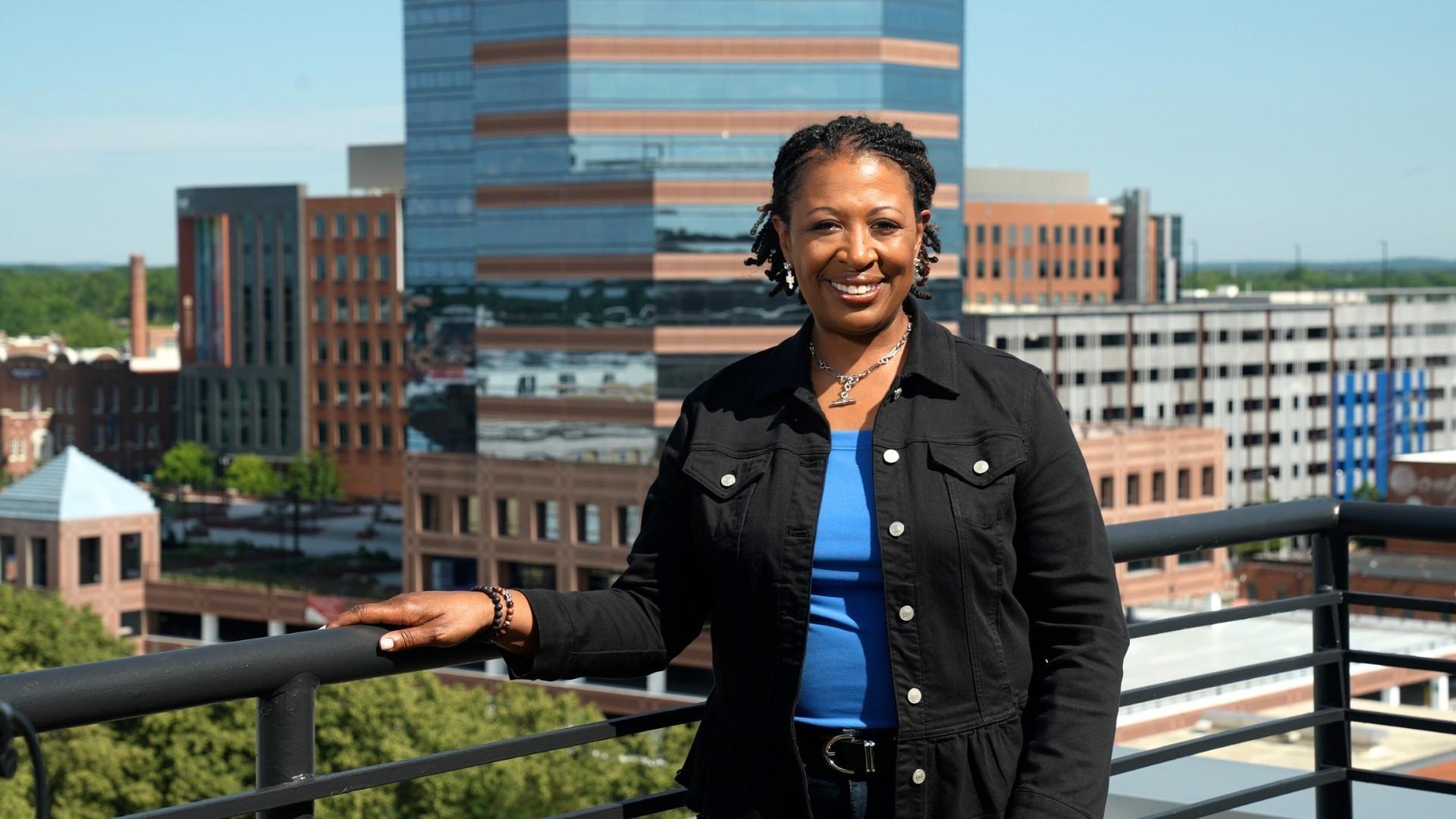 Host Deborah Holt Noel with the Durham, NC skyline behind her.