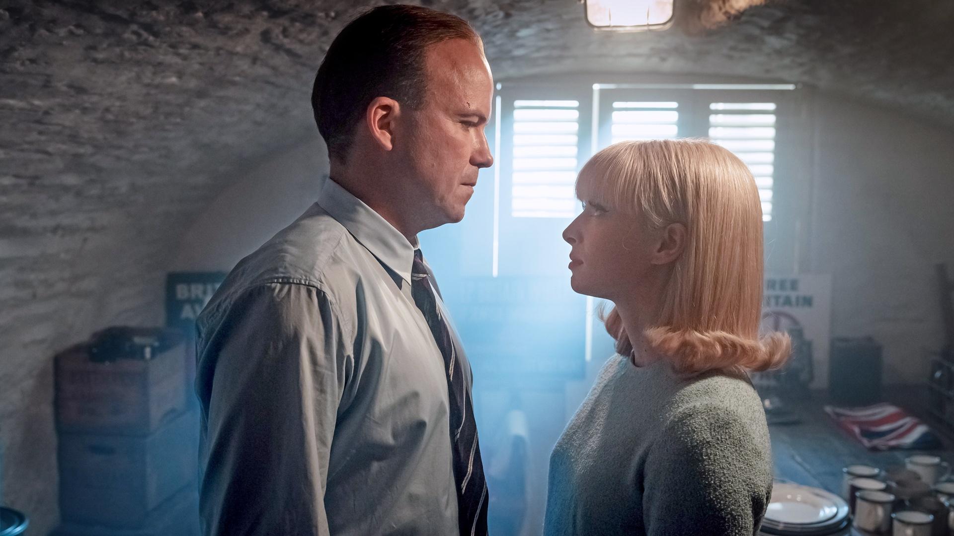A man and woman stand close to each other  in an attic as sunlight trickles in from Ridley Road on PBS