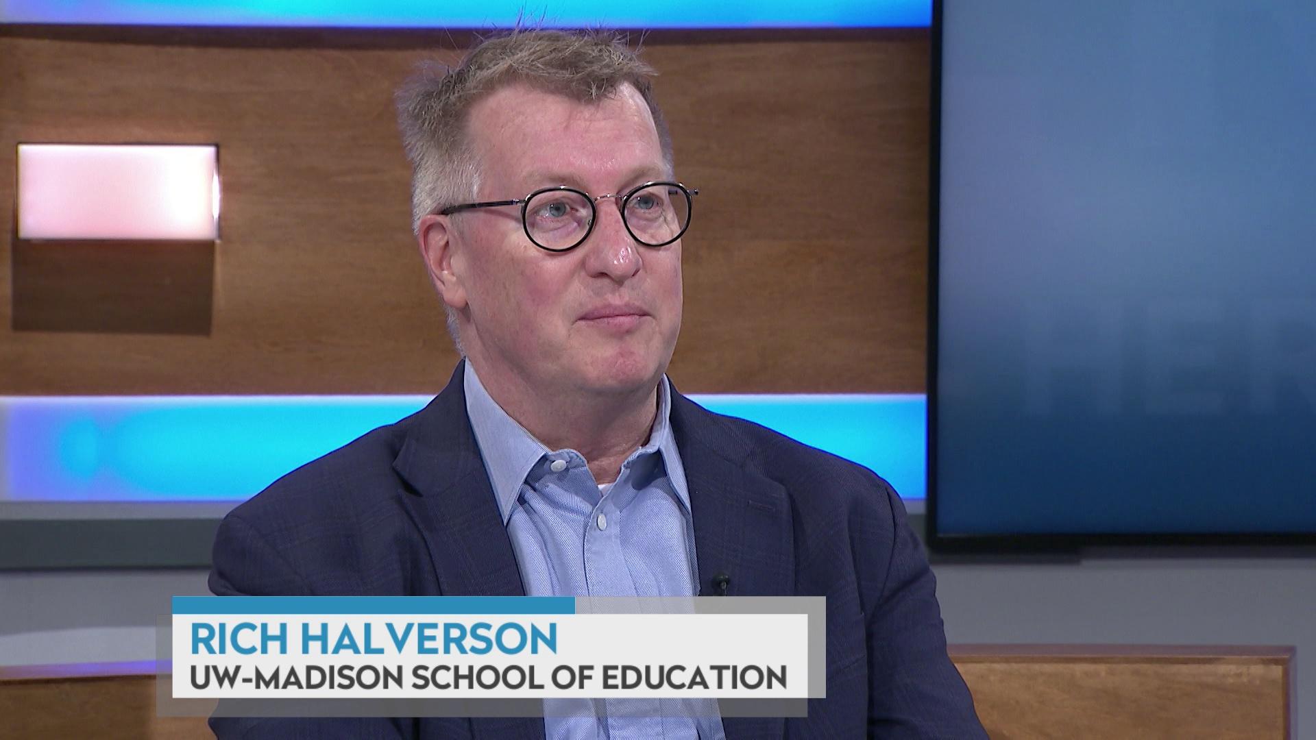 A still image shows Rich Halverson seated at the 'Here & Now' set featuring wood paneling, with a graphic at bottom reading 'Rich Halverson' and 'UW-Madison School of Education.'