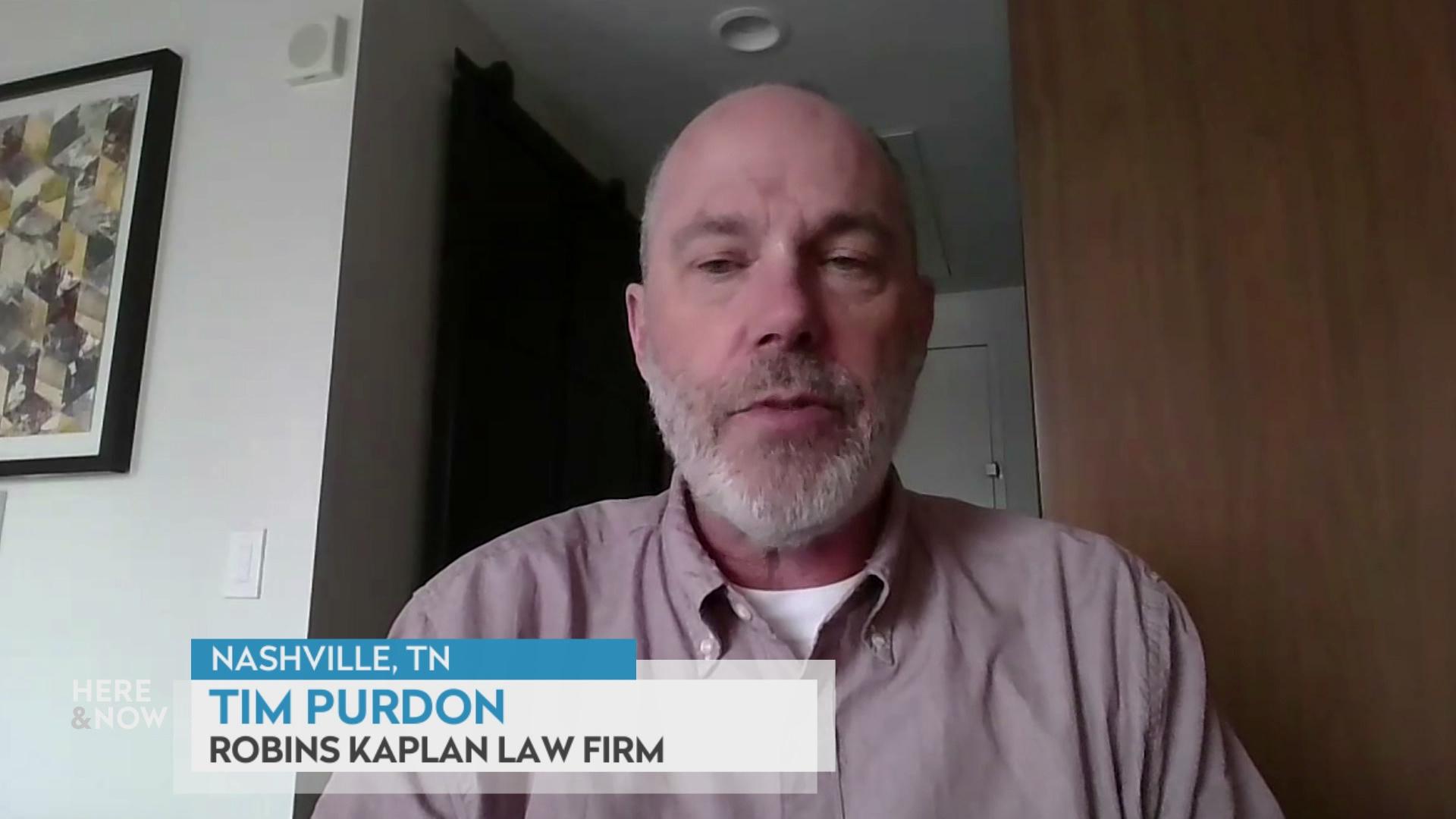 A still image from a video shows Timothy Purdon seated in front of a wooden bookshelf to his right with a graphic at bottom reading 'Nashville, TN,' 'Tim Purdon' and 'Robins Kaplan Law Firm.'