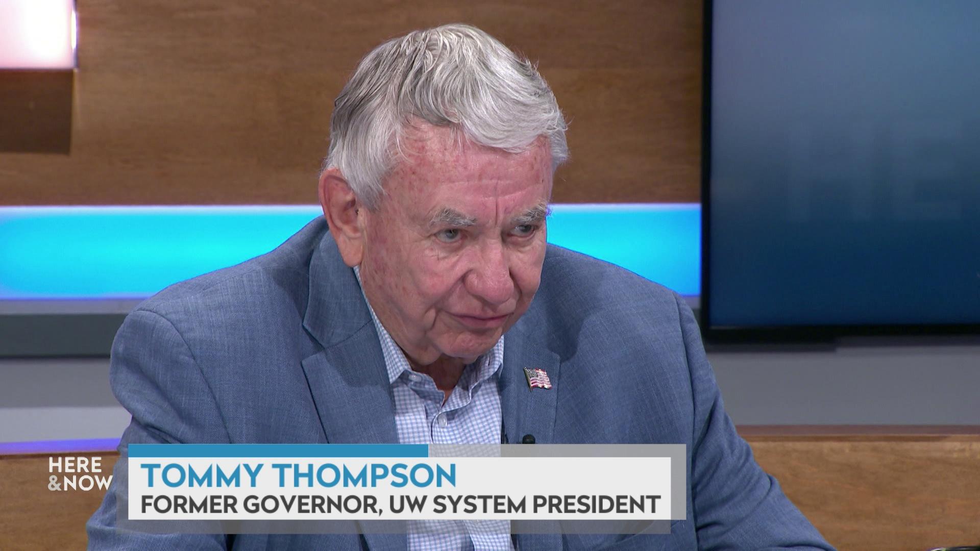 A still image shows Tommy Thompson seated at the 'Here & Now' set featuring wood paneling, with a graphic at bottom reading 'Tommy Thompson' and 'Former Governor, UW System President.'