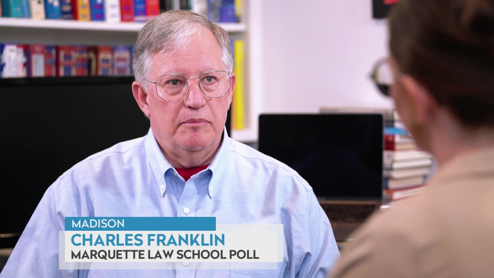 A still image shows Charles Franklin seated in front stacks of books and blank computer monitors, with a graphic at bottom reading 'Madison,' 'Charles Franklin' and 'Marquette Law School Poll.'