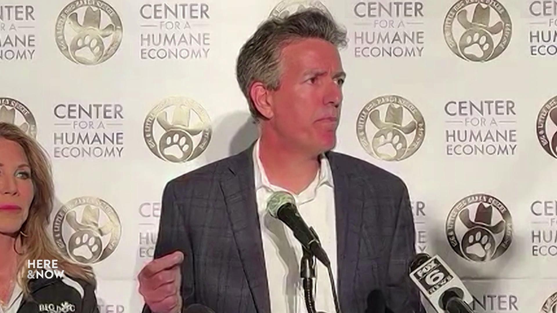 A still image shows Wayne Pacelle standing in front of several microphones at a press conference with a wall depicting several logos of the Center for a Humane Economy.