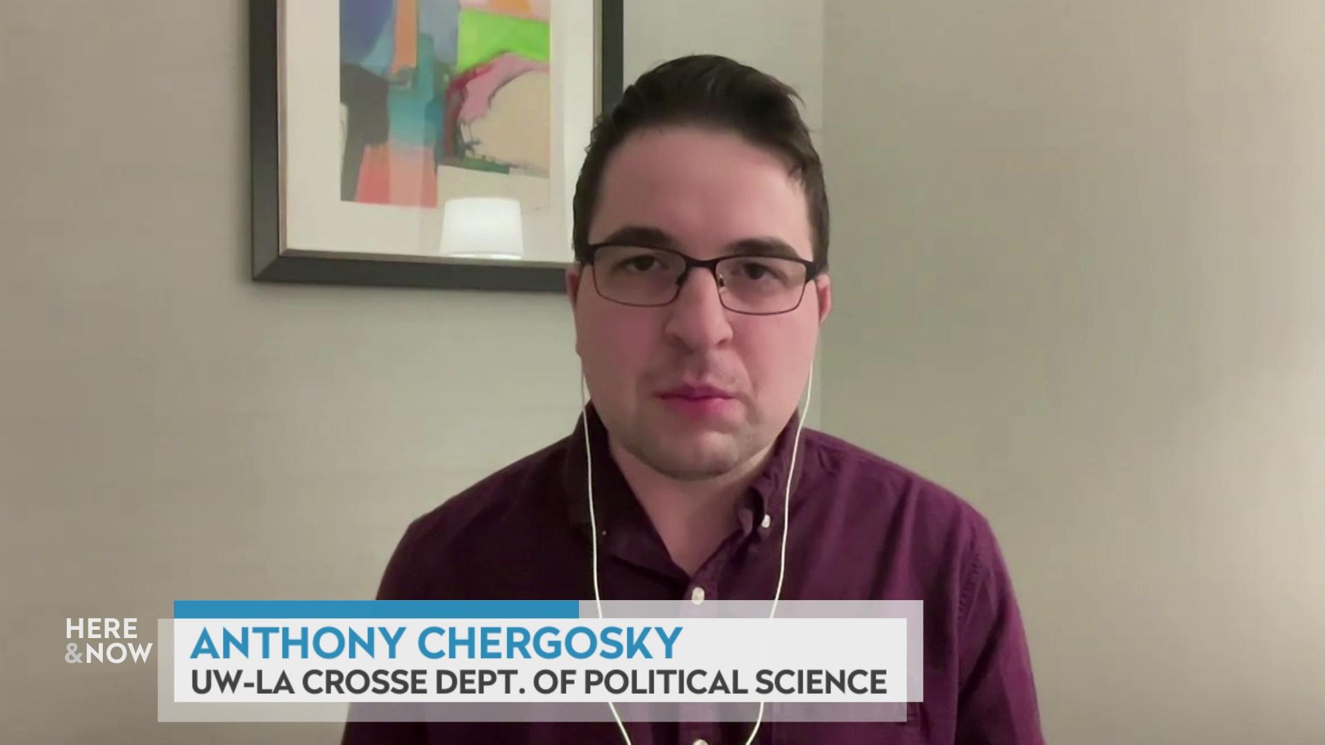 A still image from a video shows Anthony Chergosky seated in front of framed artwork on the wall with a graphic at bottom reading 'Anthony Chergosky' and 'UW-La Crosse Dept. of Political Science.'