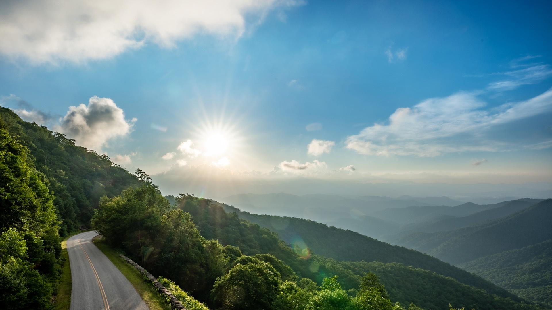 The blue ridge mountains with the sun shining brightly over them.
