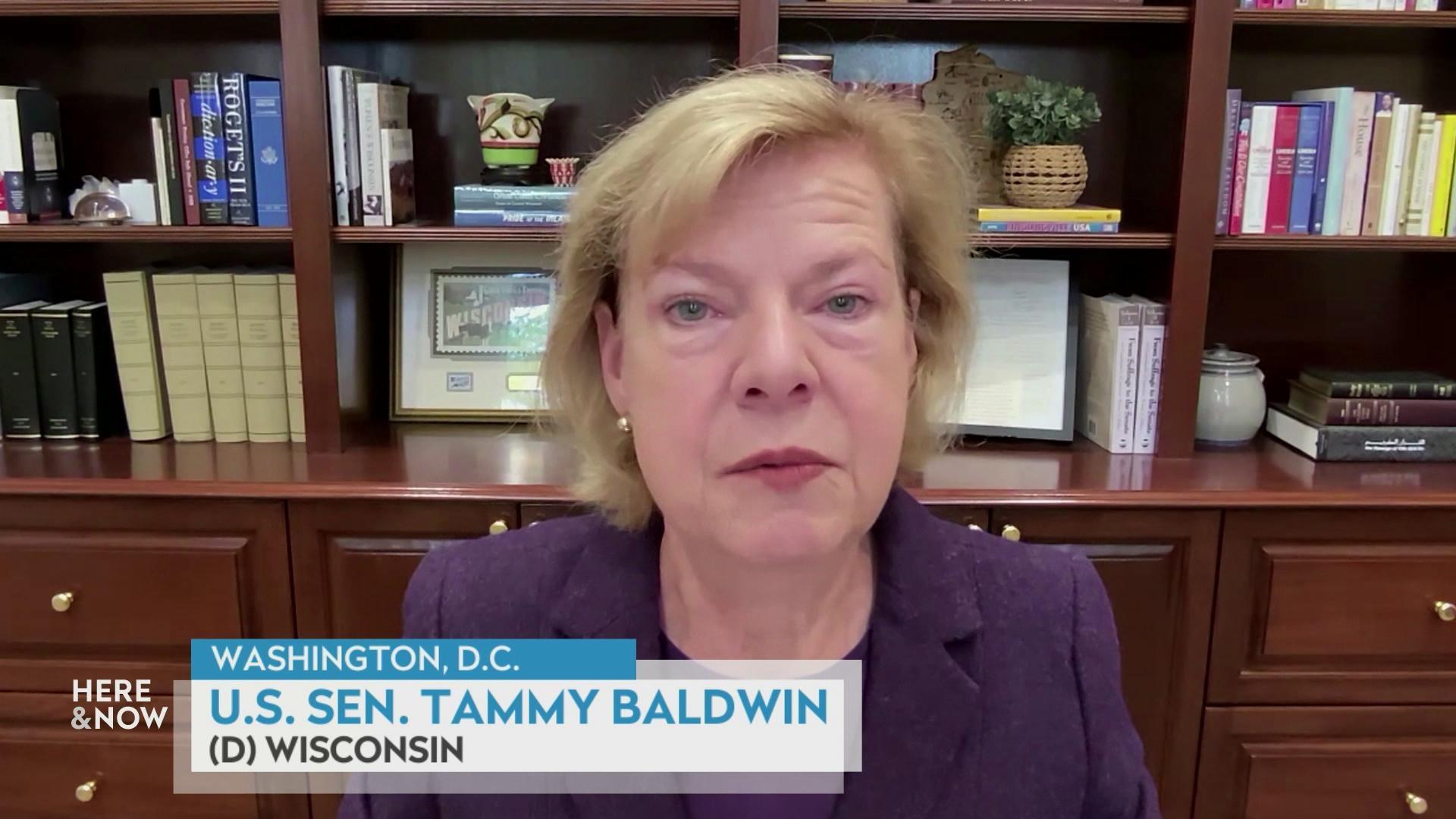 A still image shows Tammy Baldwin seated in front of a large wooden desk with many shelves, with a graphic at the bottom that reads 'Washington, D.C.' 'U.S. Sen. Tammy Baldwin' and '(D) Wisconsin.'